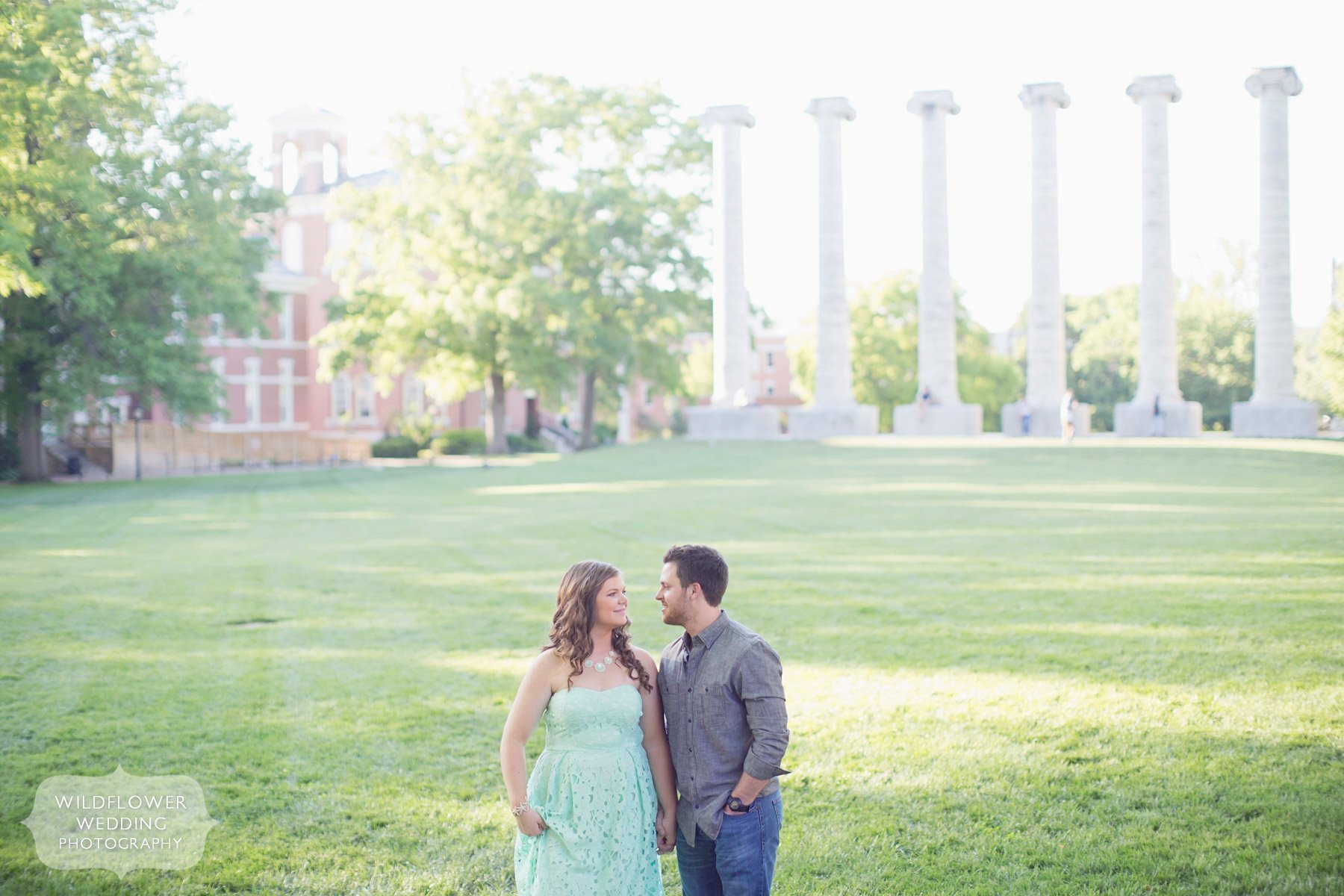 Photo of an engaged couple in front of the historic columns on the quadrangle of Mizzou campus in Columbia, MO.