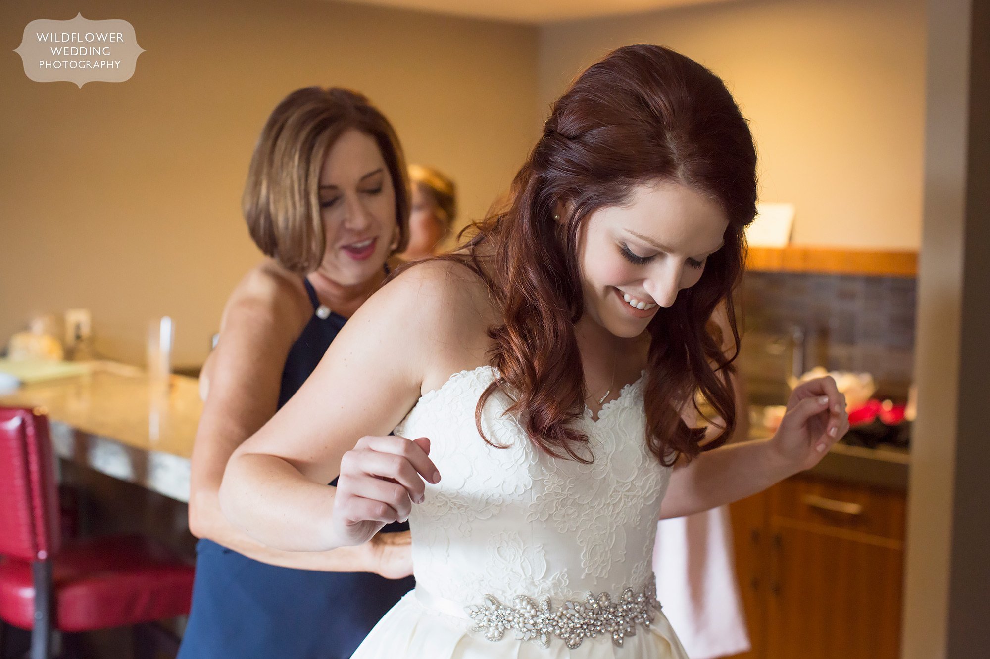 Emotional photojournalism style wedding photo of the bride putting her dress on before her summer outdoor wedding in Columbia, MO.