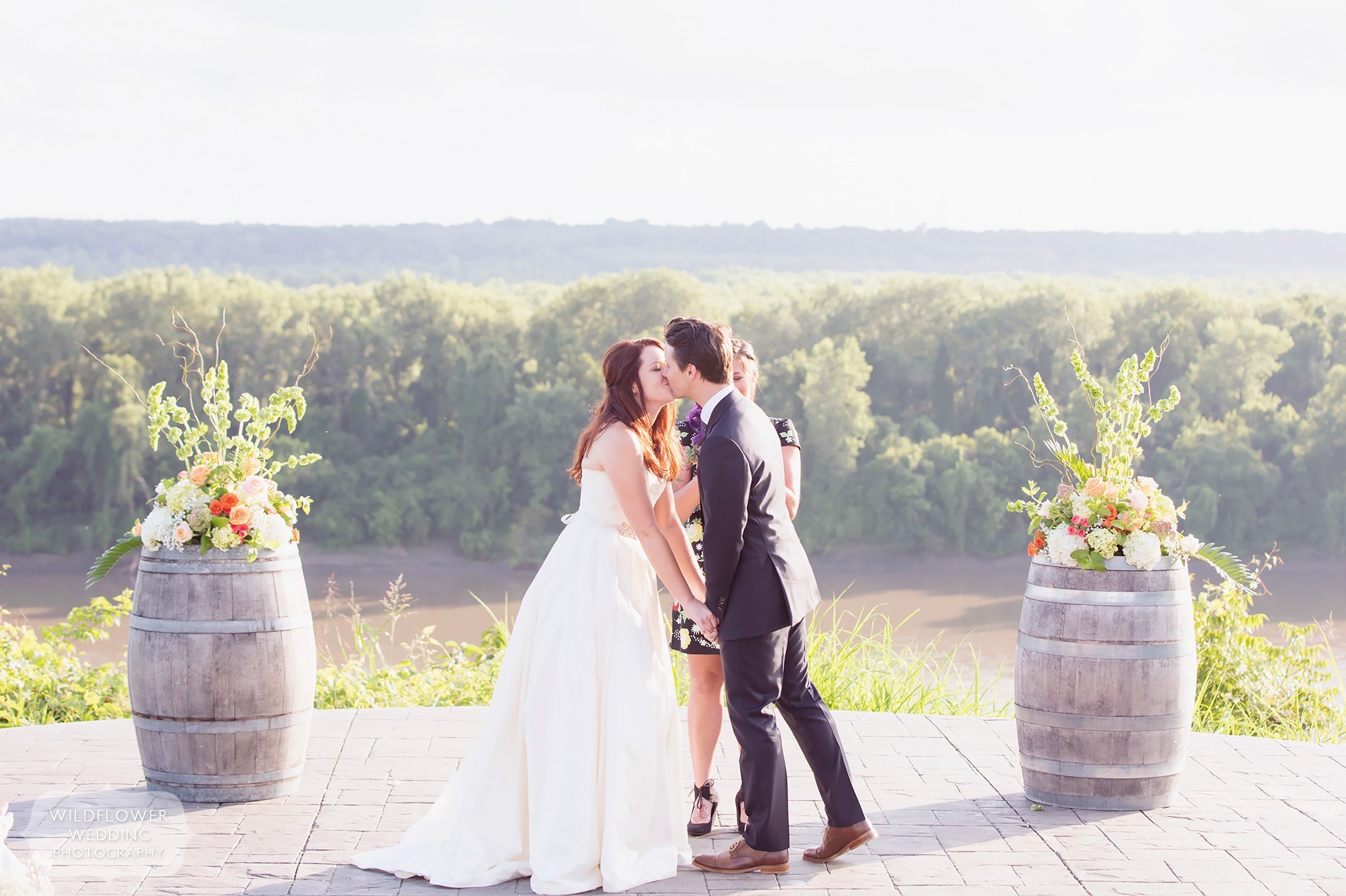 The bride and groom kiss during their outdoor wedding ceremony at the Les Bourgeois Winery in Rocheport, MO.