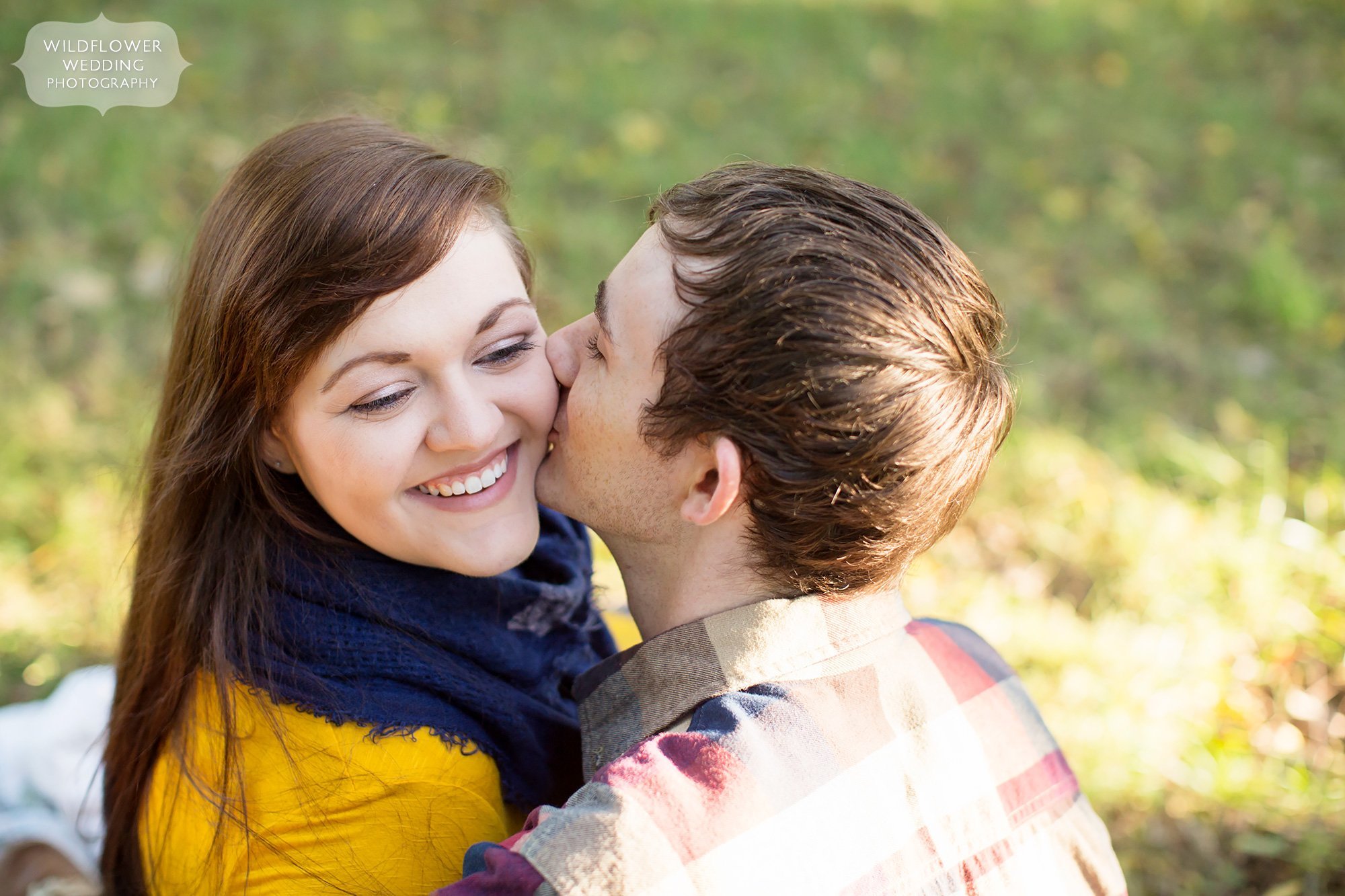 Boy kissing girl on the cheek during their autumn engagement session at Nifong Park in Columbia, MO.