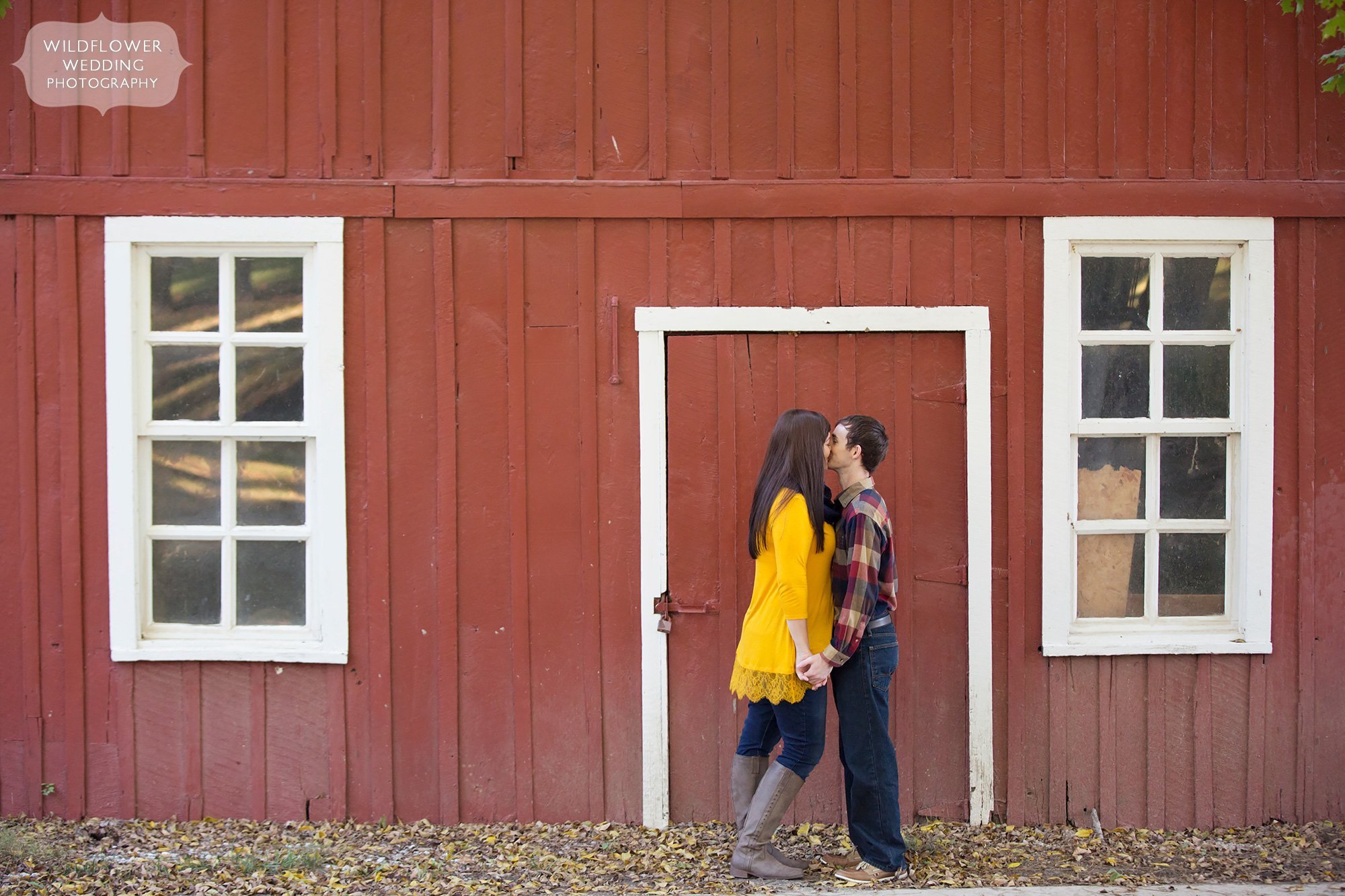 Couple kissing in front of the red barn at Nifong Park in Columbia, MO in October.