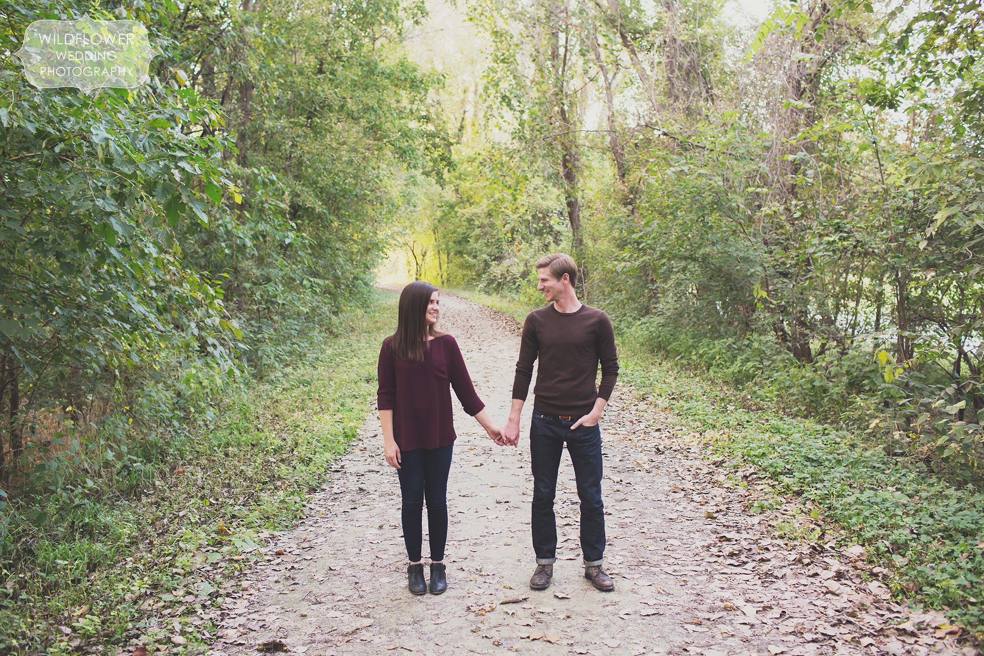 Couple holding hands on the Katy Trail at Cooper's Landing during their hipster engagement photo shoot.