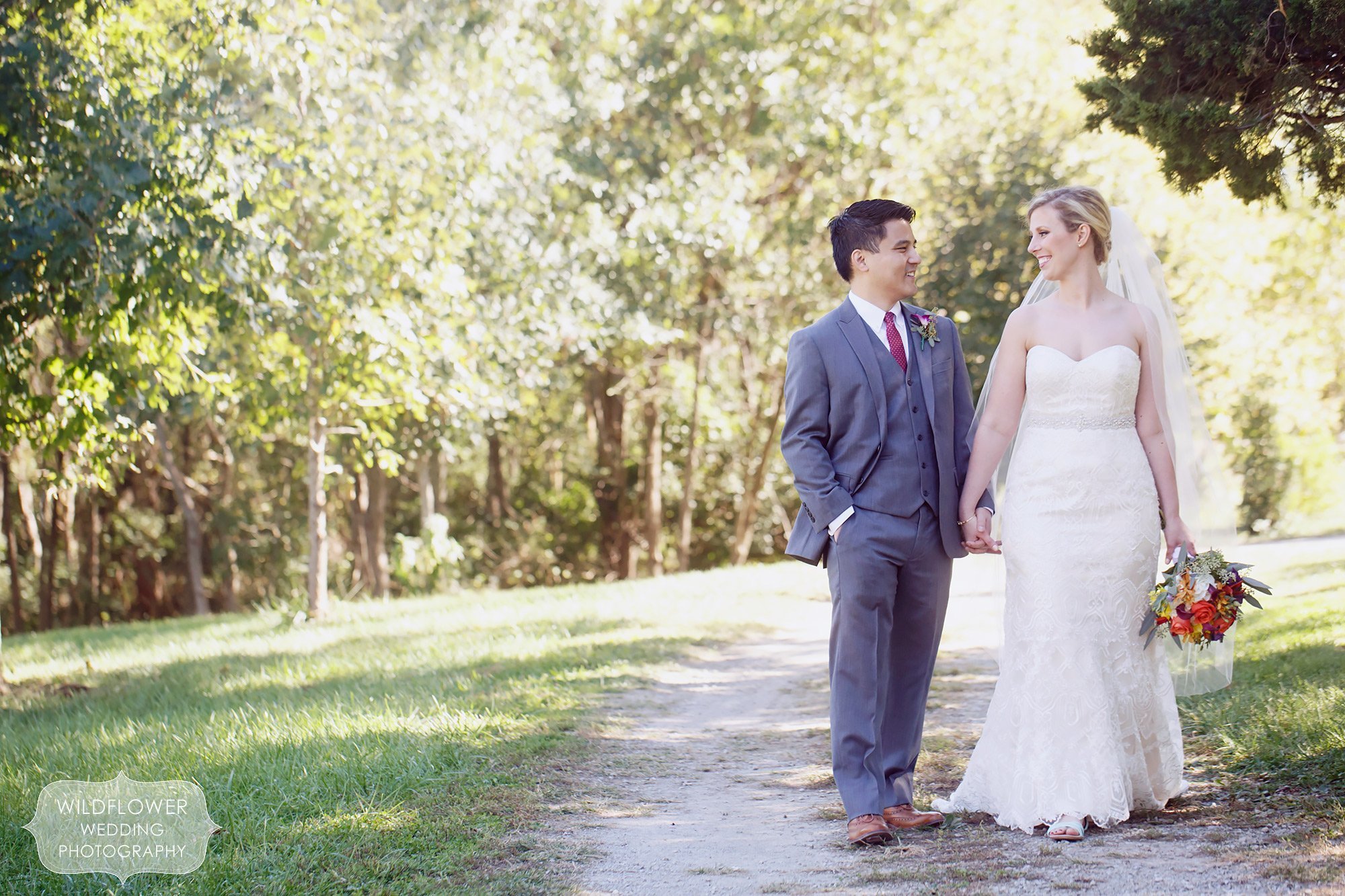 Candid wedding portrait of bride and groom walking down a path at their Missouri backyard wedding.