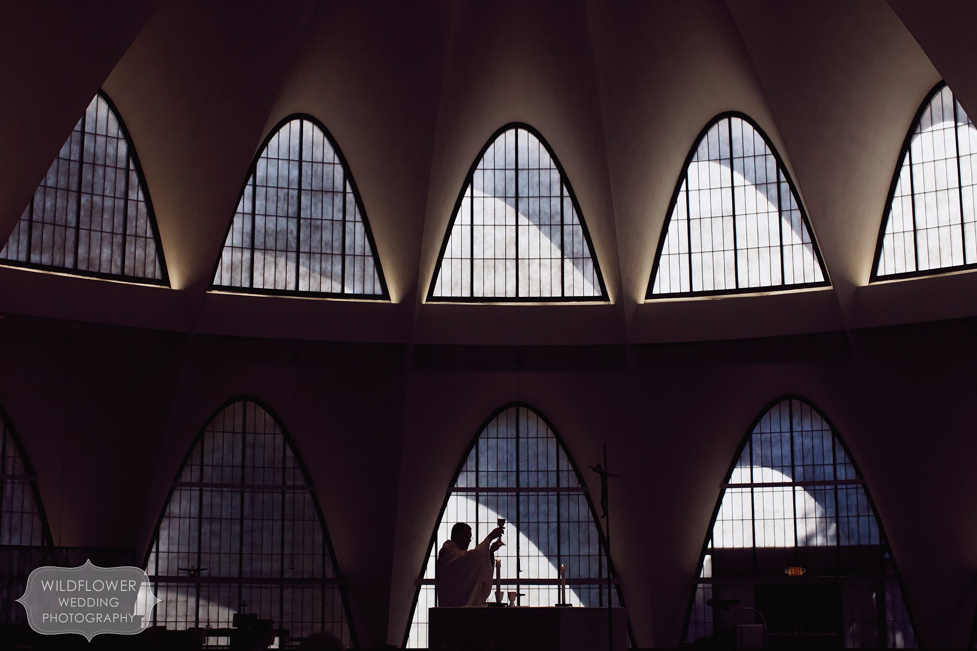 Fine art style wedding photo of priest silhouetted at St. Anslem church in St. Louis, MO.
