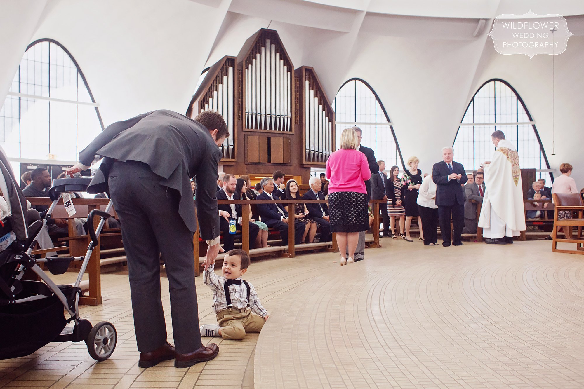 Funny wedding ceremony photo of a toddler on the floor at the St. Anselm church at the Priory School.