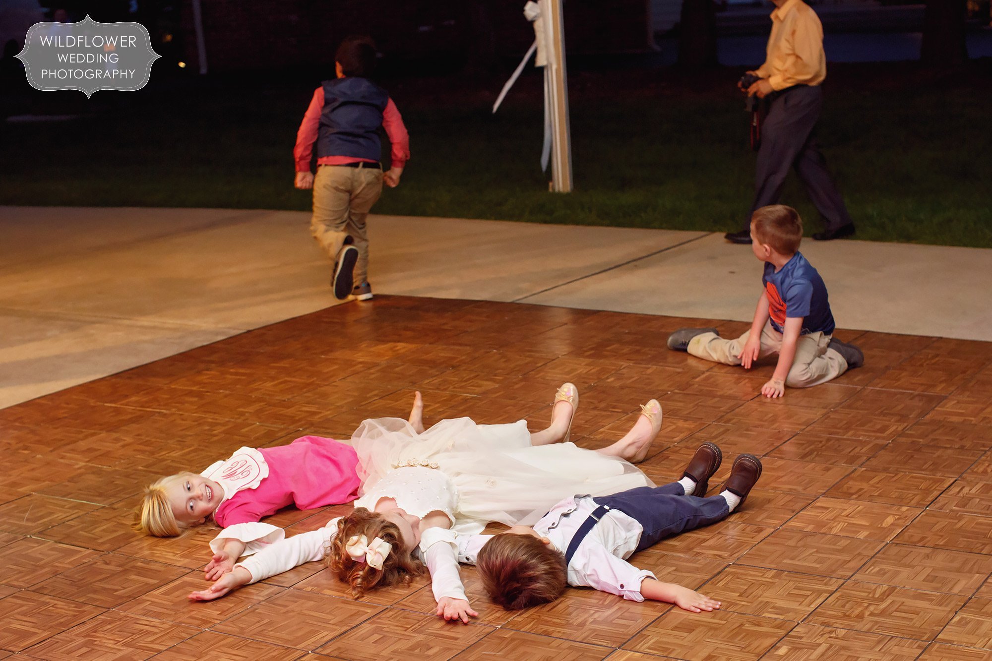 Funny wedding reception photo of kids laying on the dance floor at this tented backyard wedding in St. Louis.