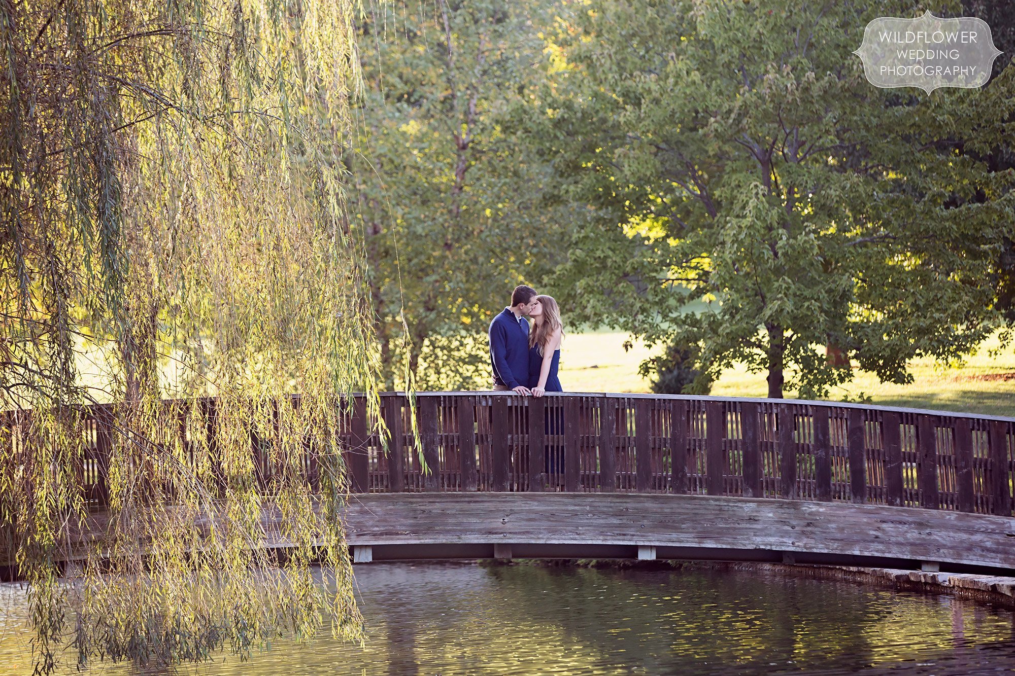 Couple kisses on the bridge at Loose Park in KC, MO.