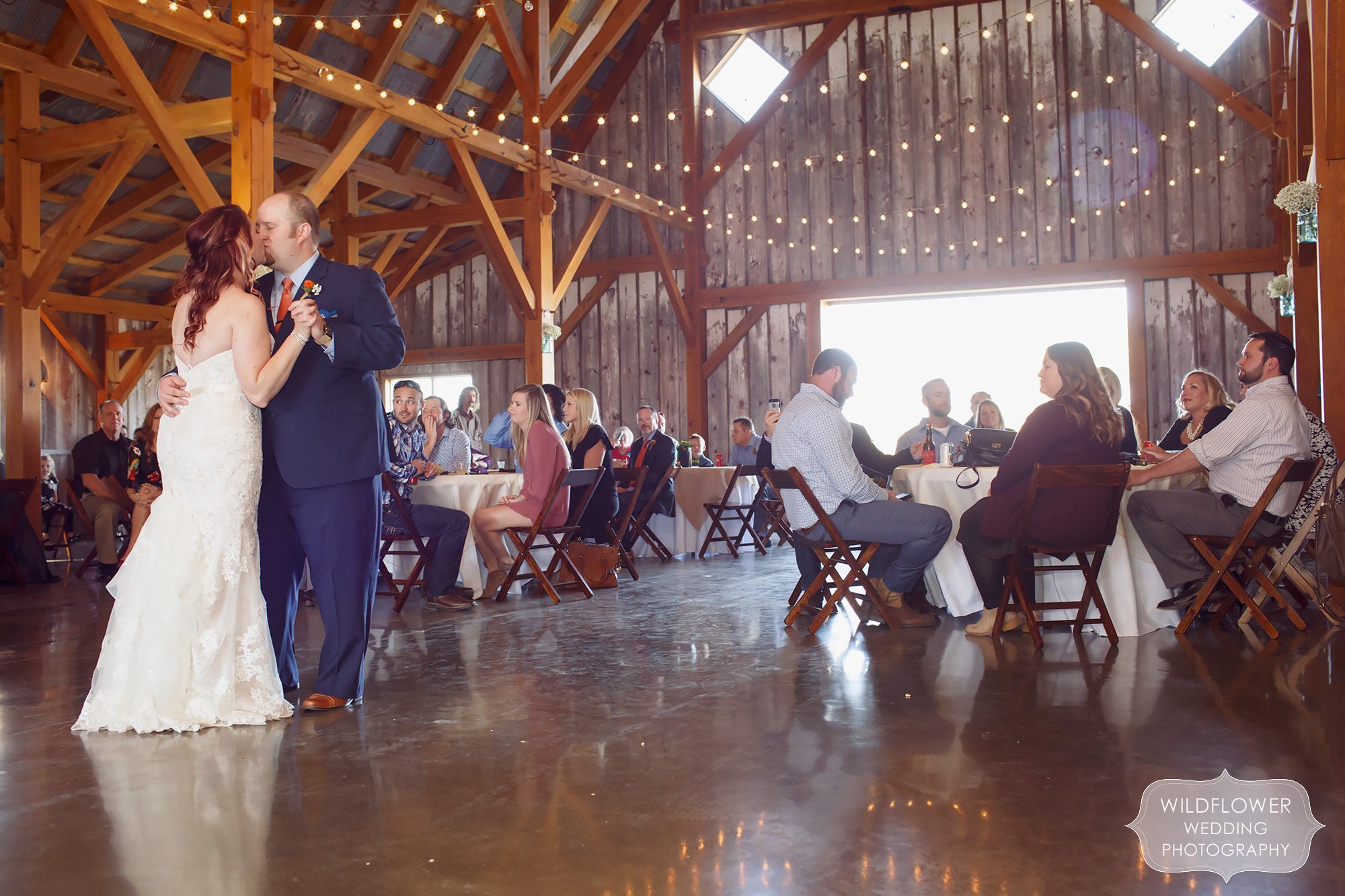 The bride and groom kiss during their first dance at this barn wedding reception just north of KC, MO.