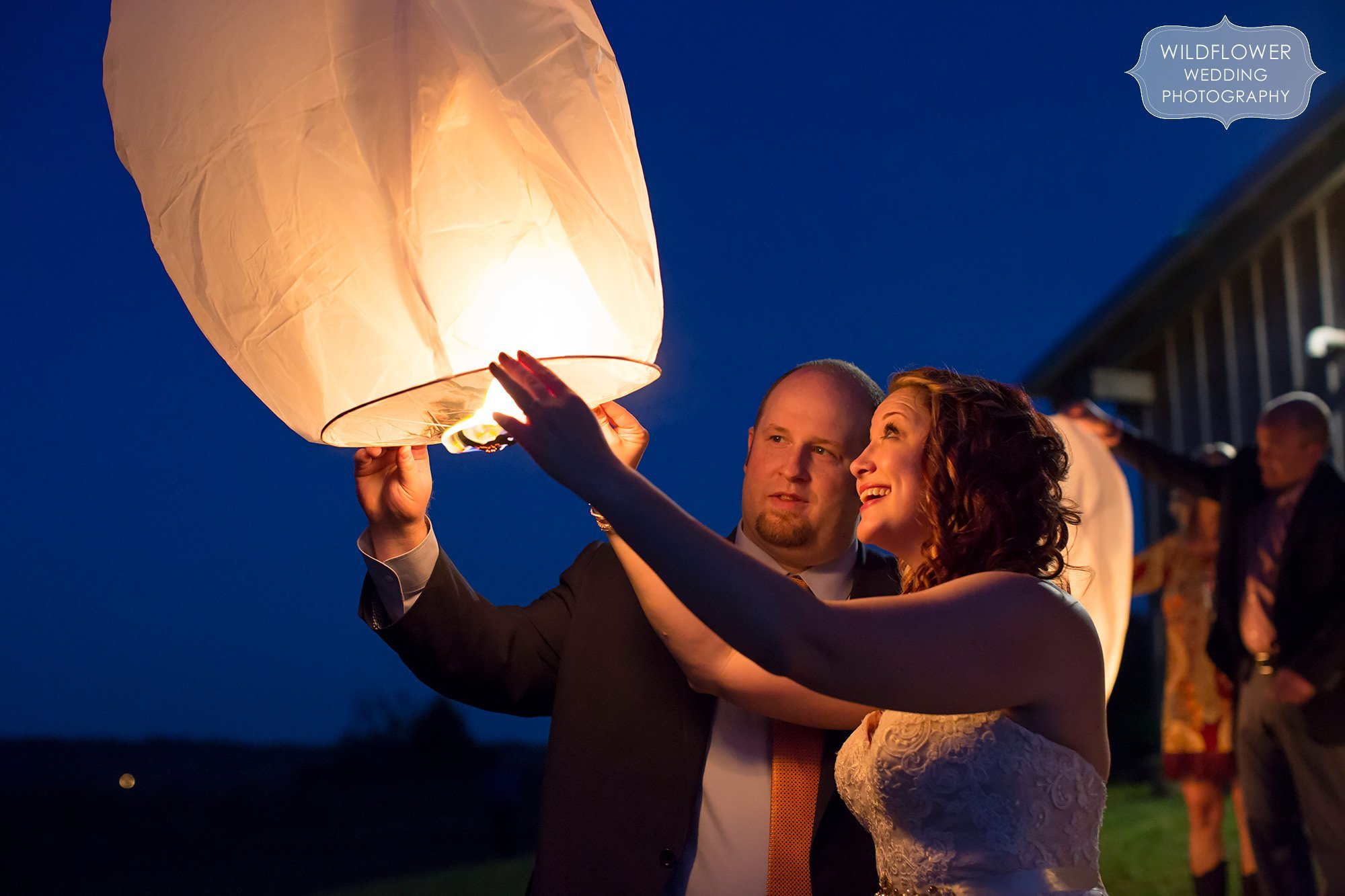 The bride and groom set off their Chinese wish lantern behind the Schwinn Produce Farm barn in Leavenworth, KS.