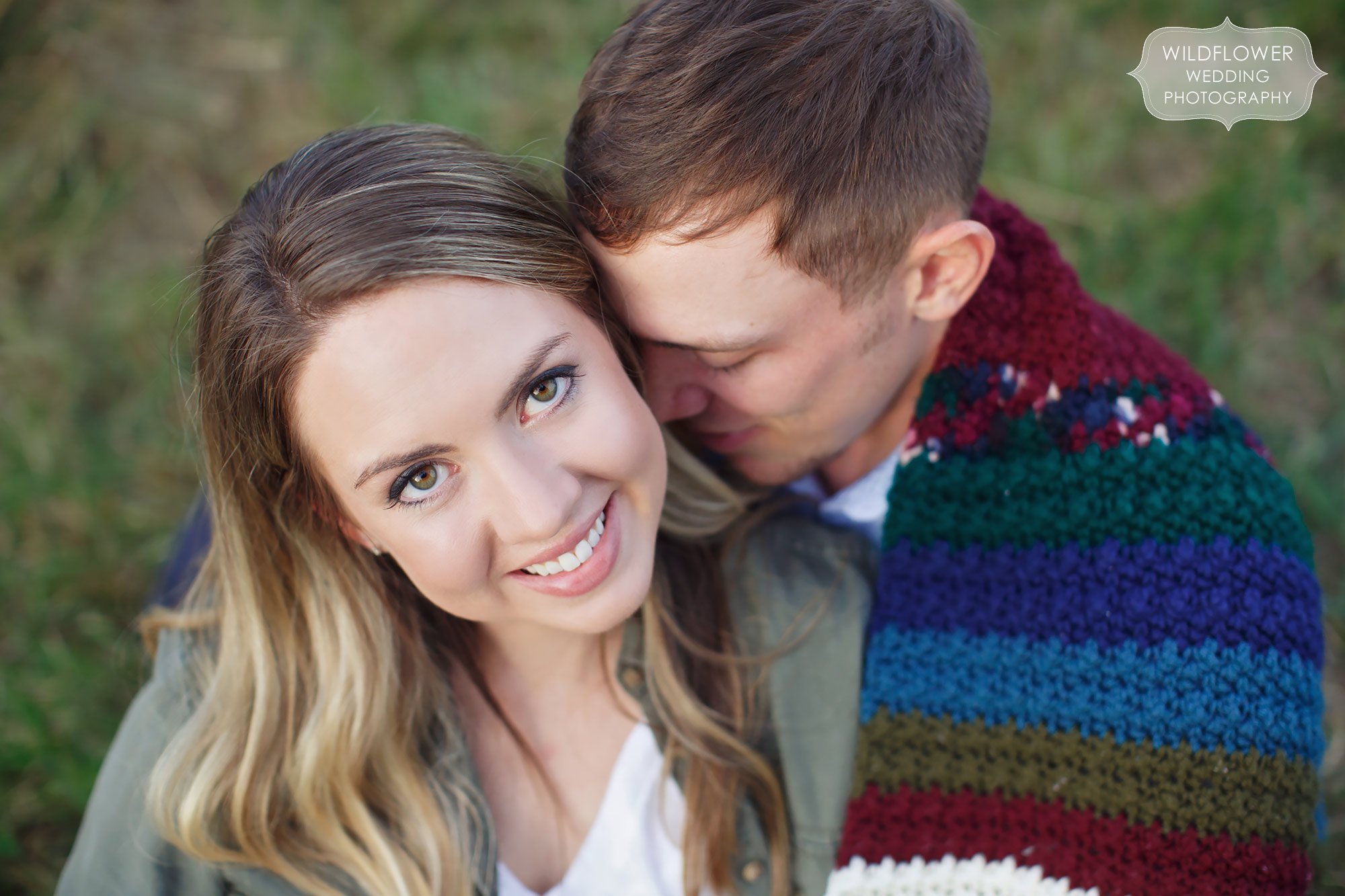 Anthropologie style winter engagement photo session with blanket and girl looking up at camera.