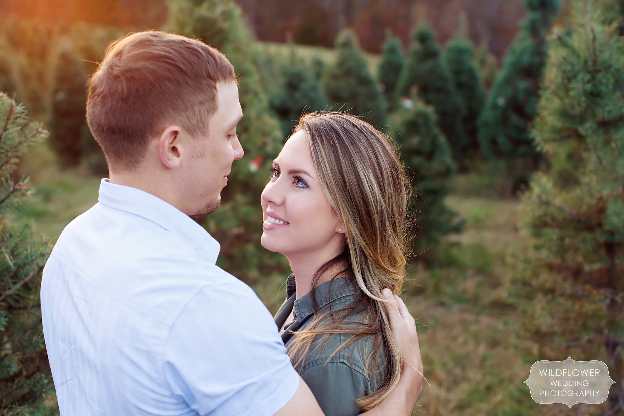 Couple looking at each other romantically during this winter engagement session in the pine trees in Columbia, MO.