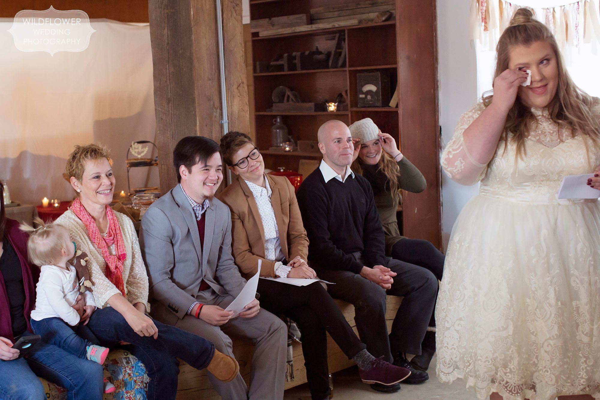 Candid moments of guests and family watching the winter wedding ceremony in the barn.