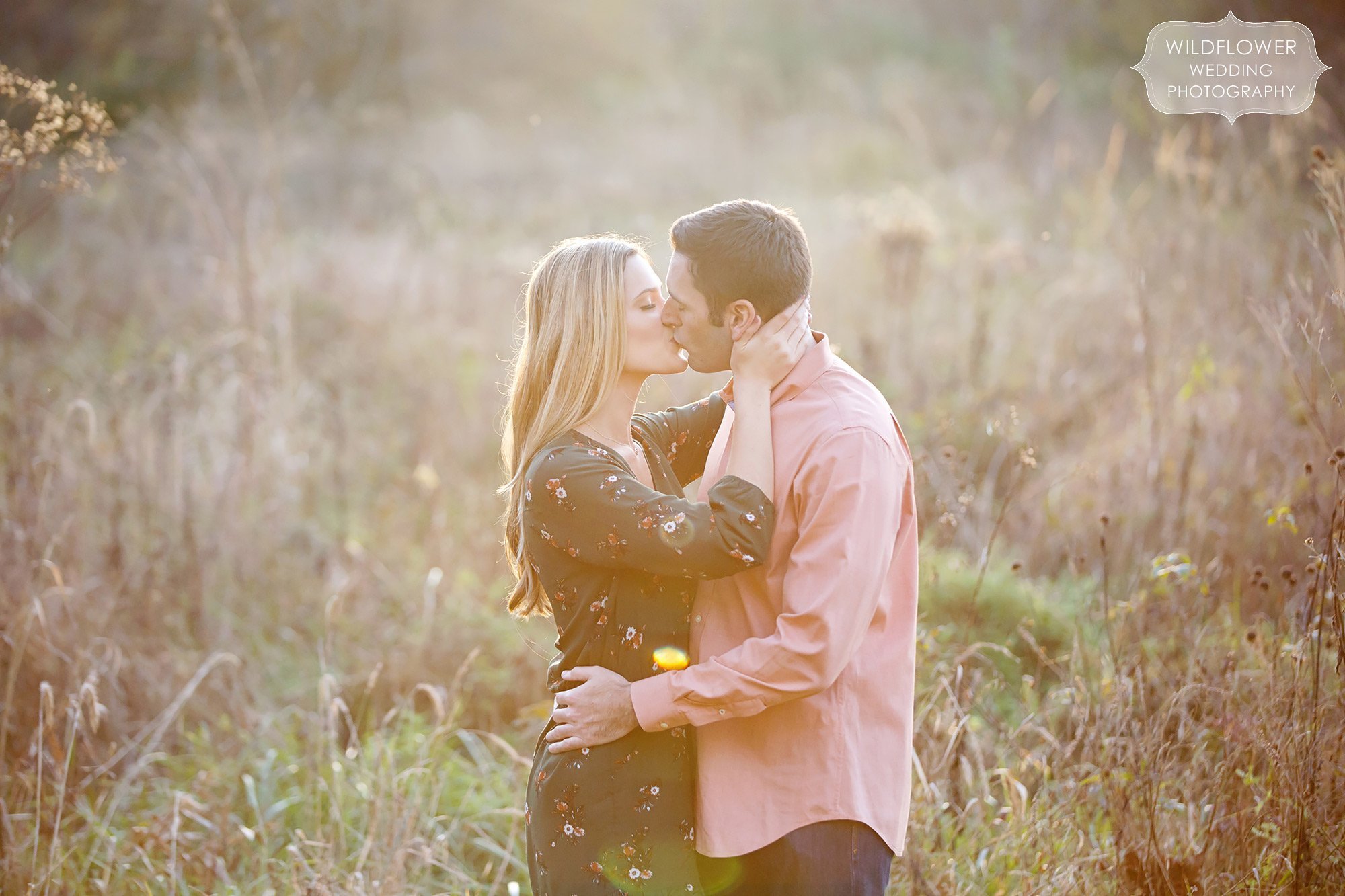Sexy engagement photo of the couple kissing in a tall grass field at sunset in Columbia, MO.