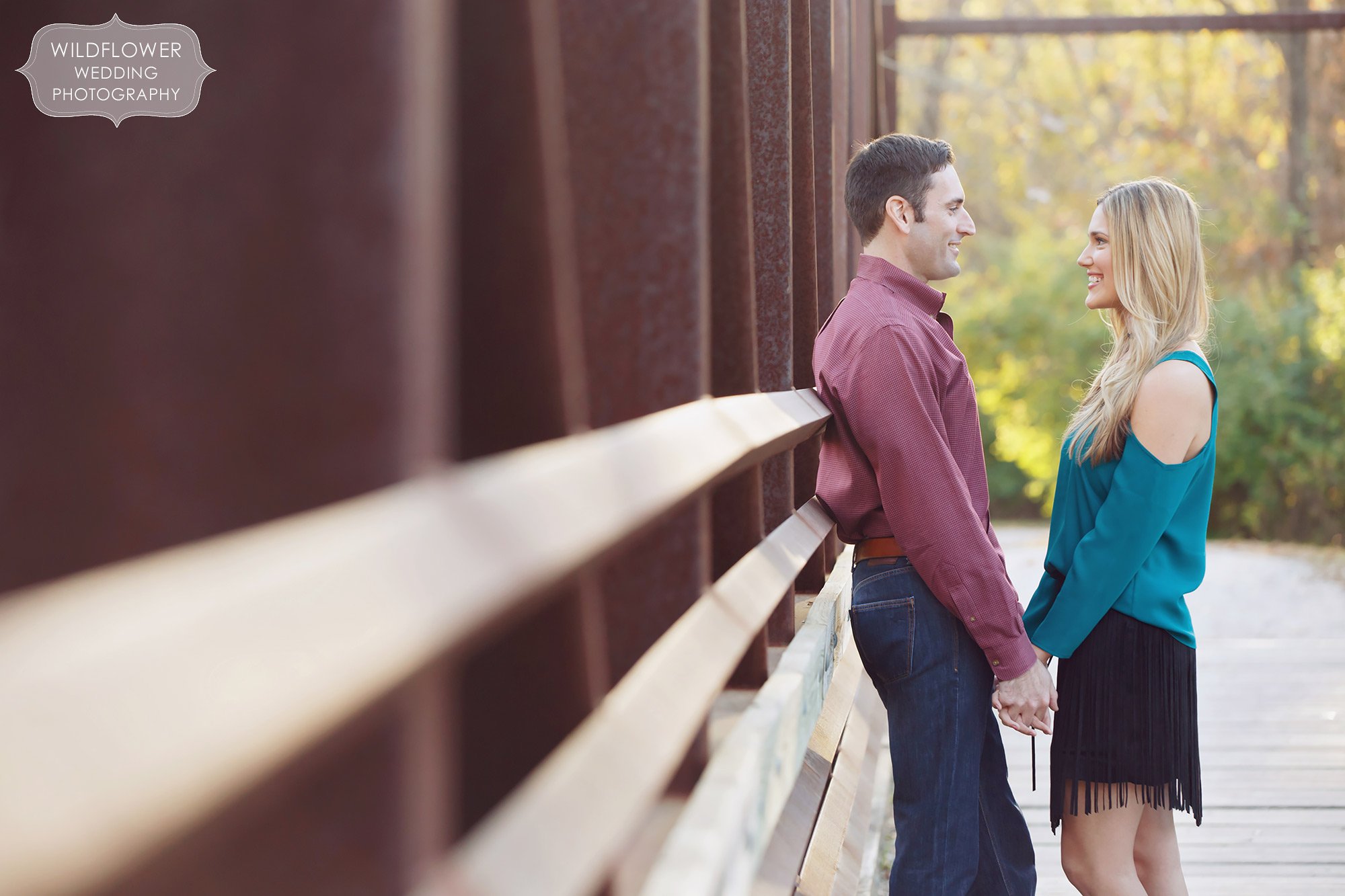 Couple poses on a bridge during their Anthropologie engagement photography session at Grindstone Park.