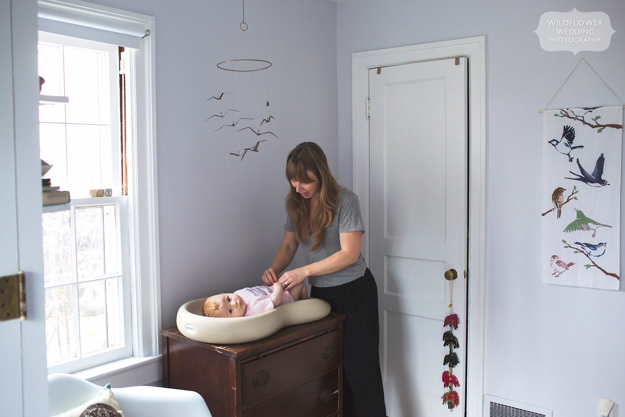 Candid photo of mother changing baby's diaper on Keekaroo Peanut at home during photo shoot in MO.