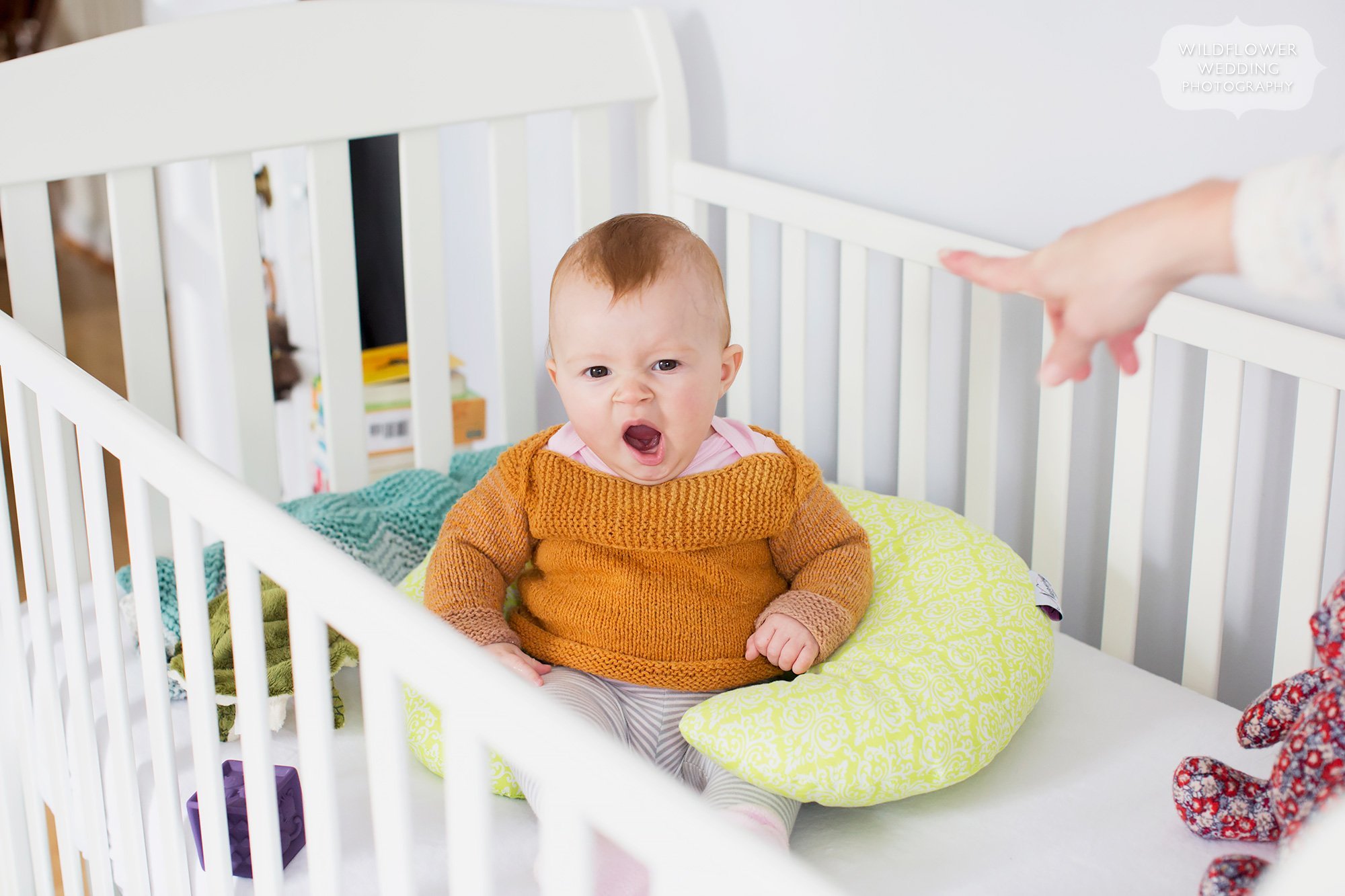 Funny photo of baby Laila yawning in her crib while Mom points to her.
