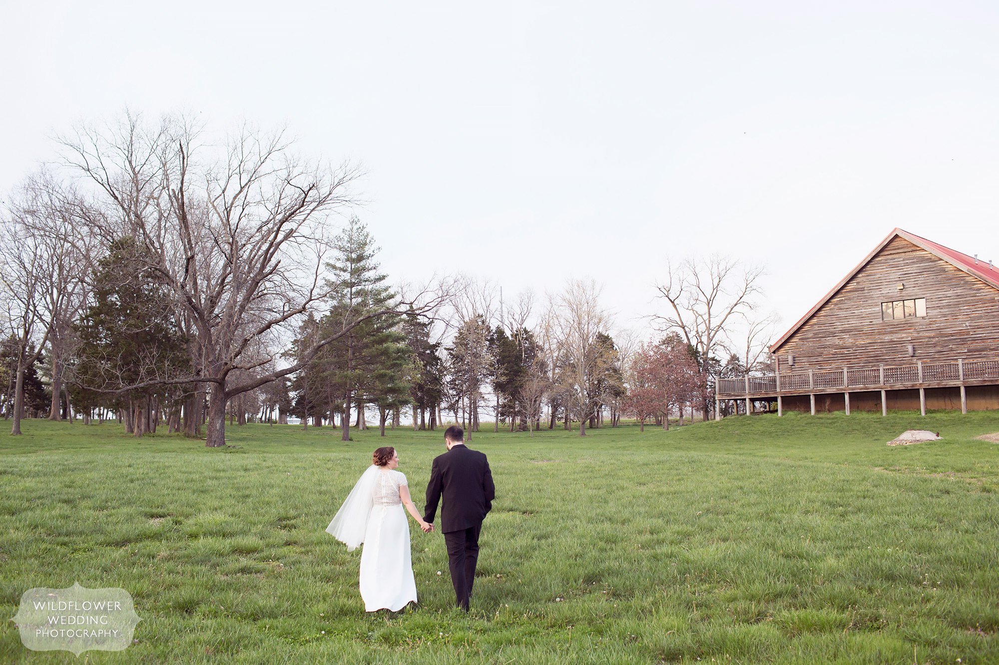 Bride and groom walk through a field at Nifong Park after their elopement.