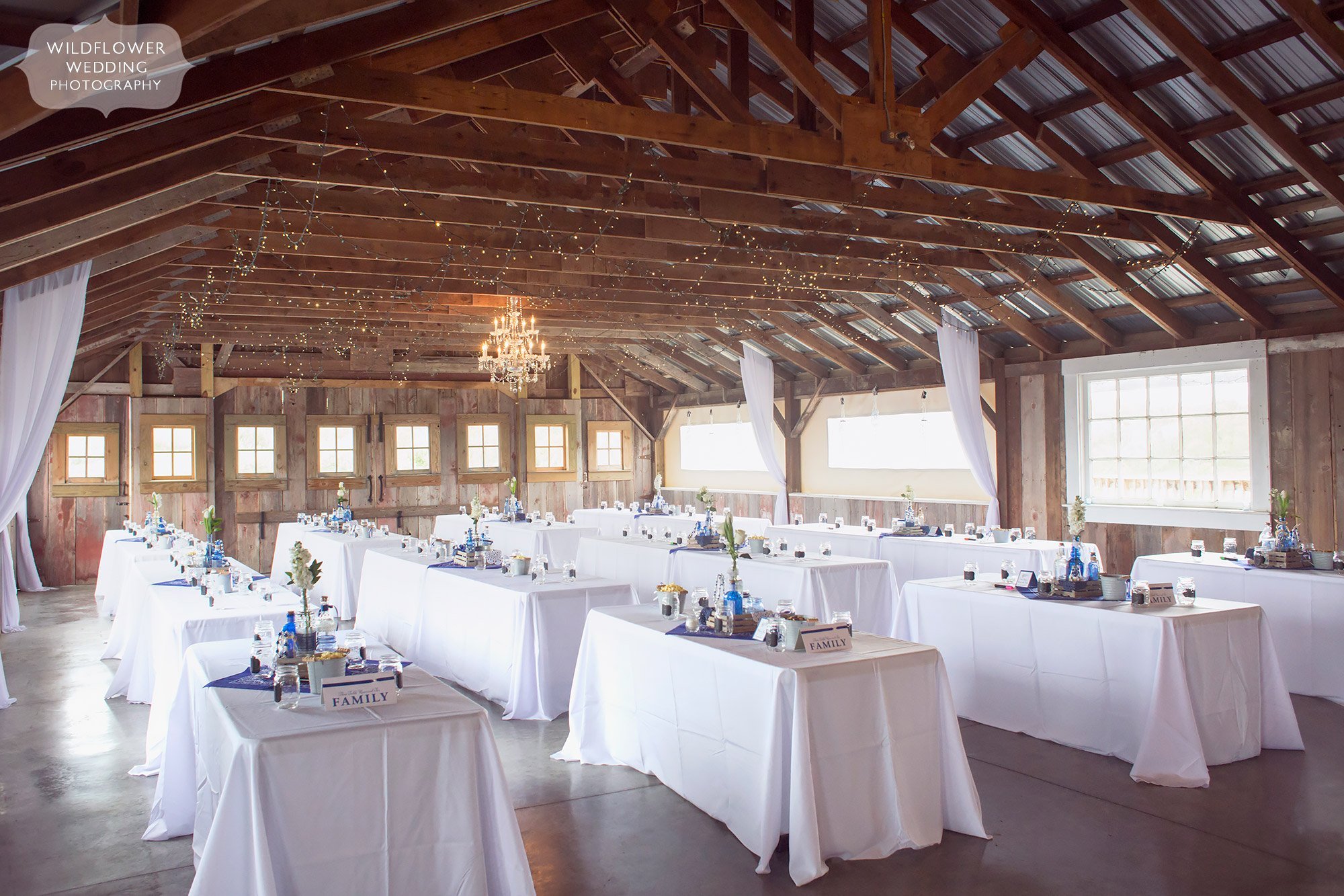 Family style tables are set up inside of the Weston Red Barn for this farm wedding in MO.