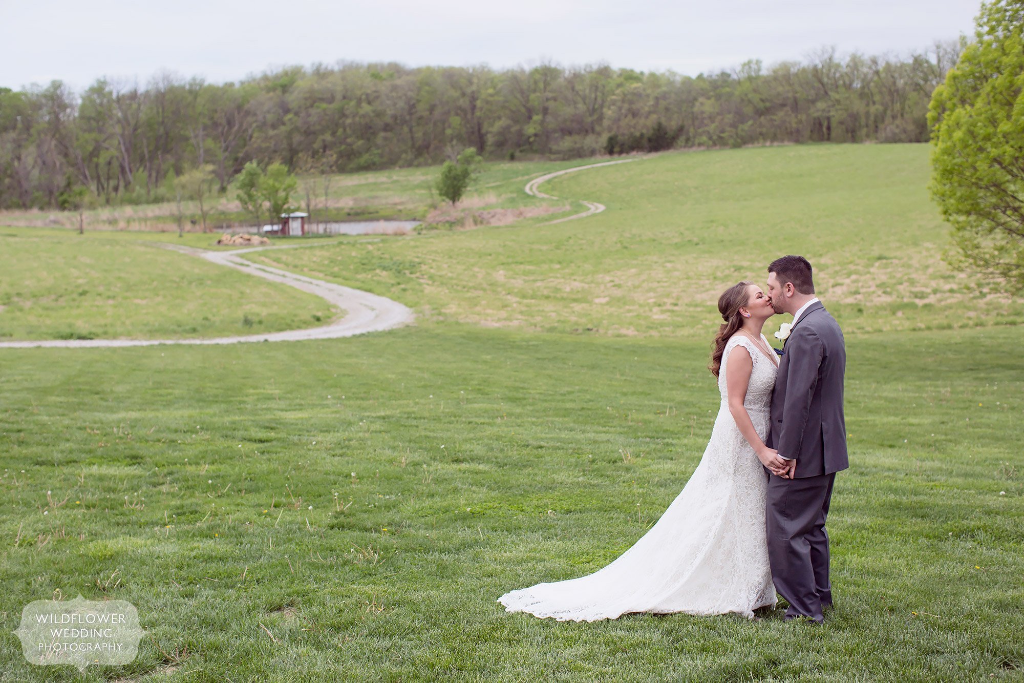 Natural wedding portrait of the bride and groom kissing with an S curve behind them at this farm wedding north of KC.