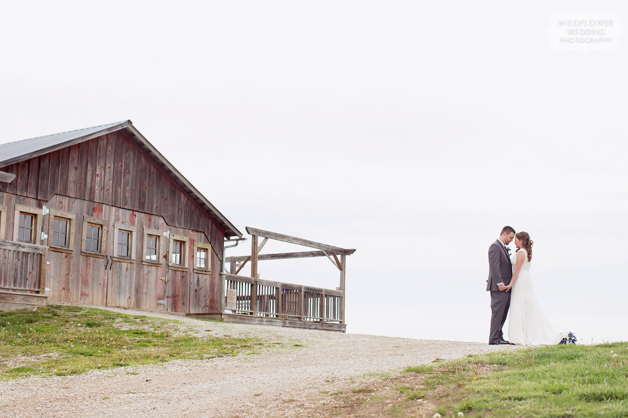 Natural wedding photography of the bride and groom outside of their barn wedding venue with a porch in Weston.