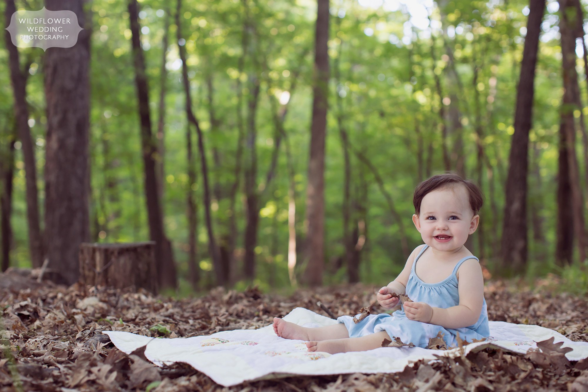 Baby sits on a picnic blanket in the middle of the woods during this family photo session in Columbia.