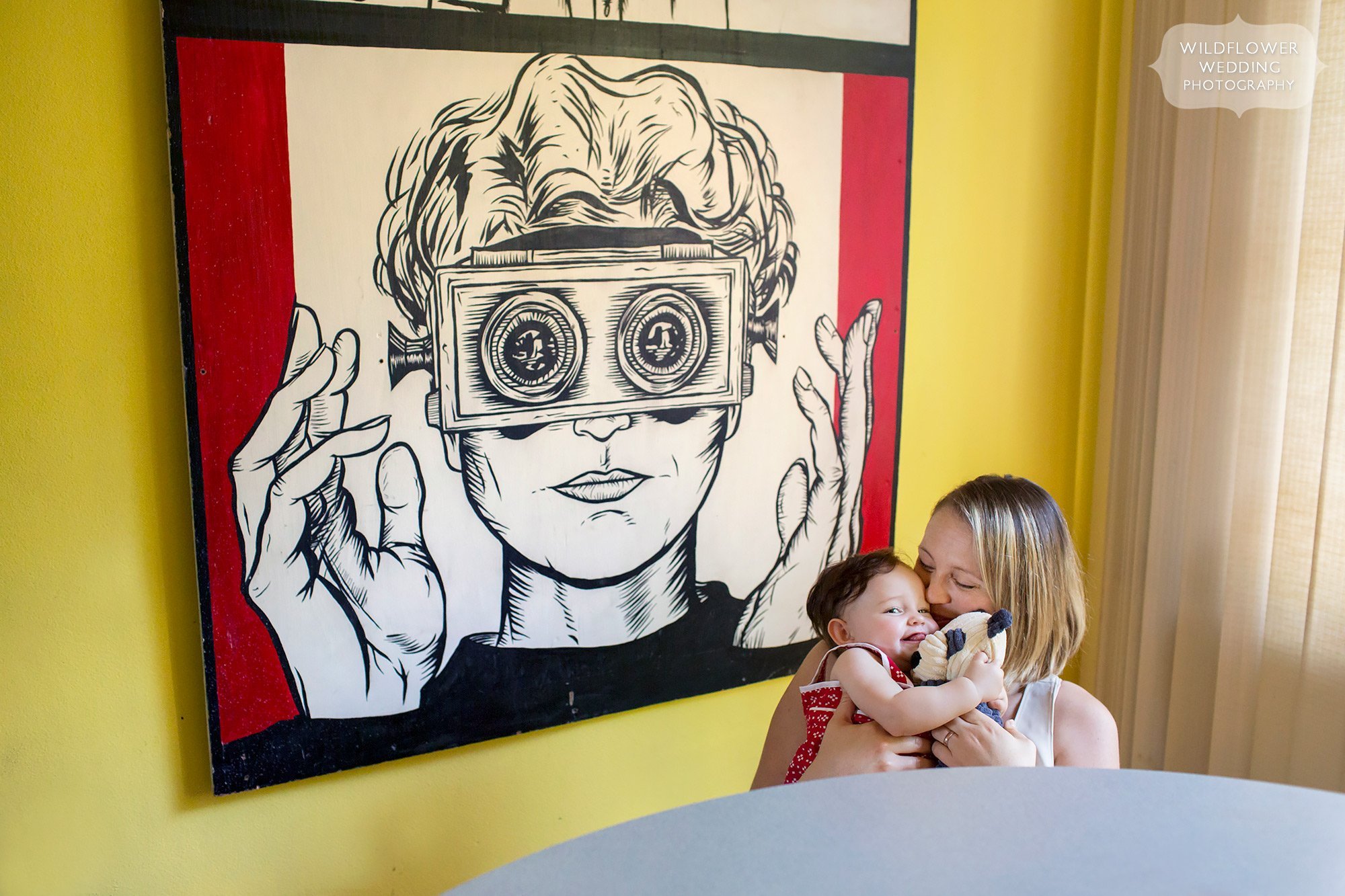 Artistic family photography at home with large pop art behind mom and baby.