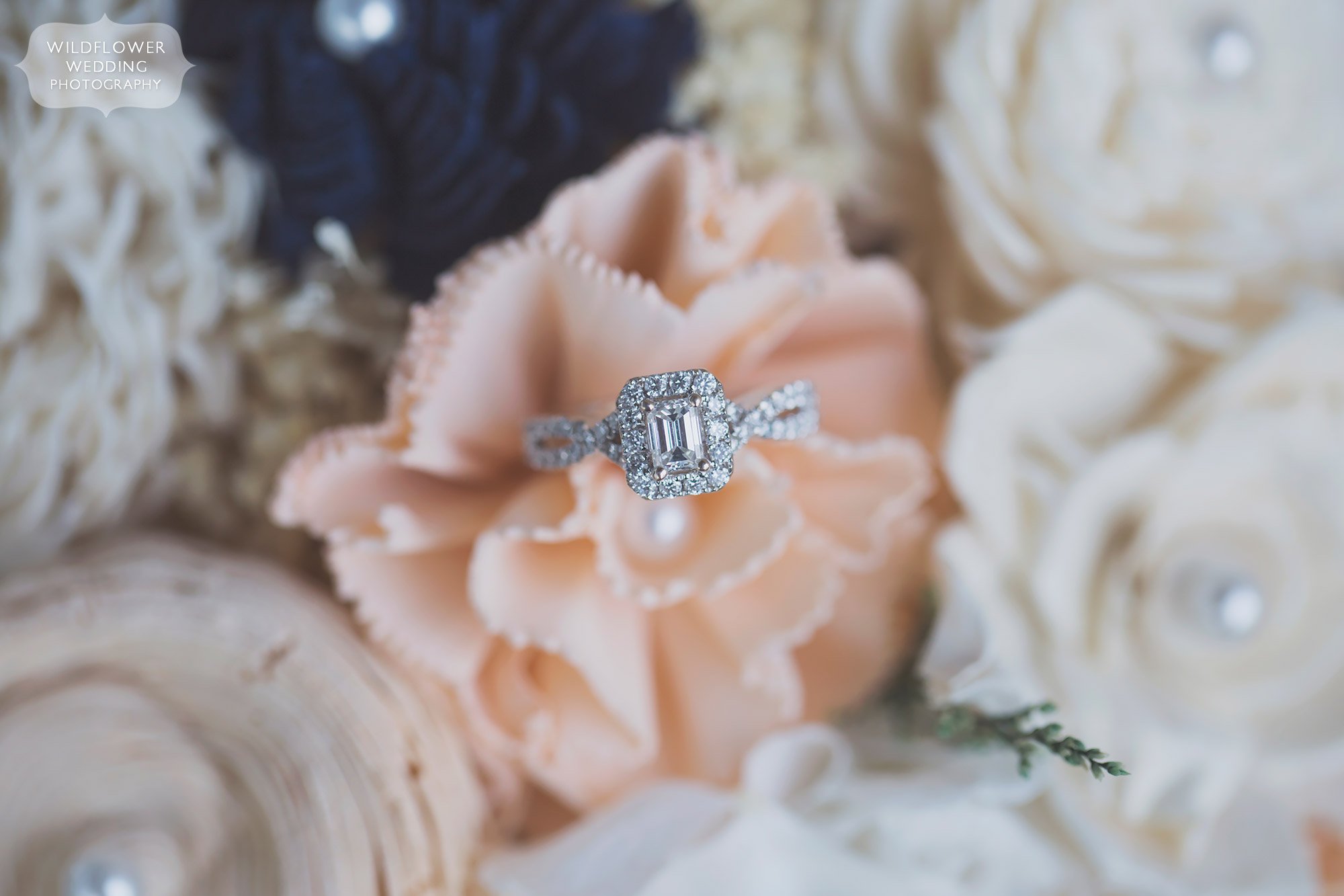 Country wedding engagement ring photo on a wooden flower bouquet.