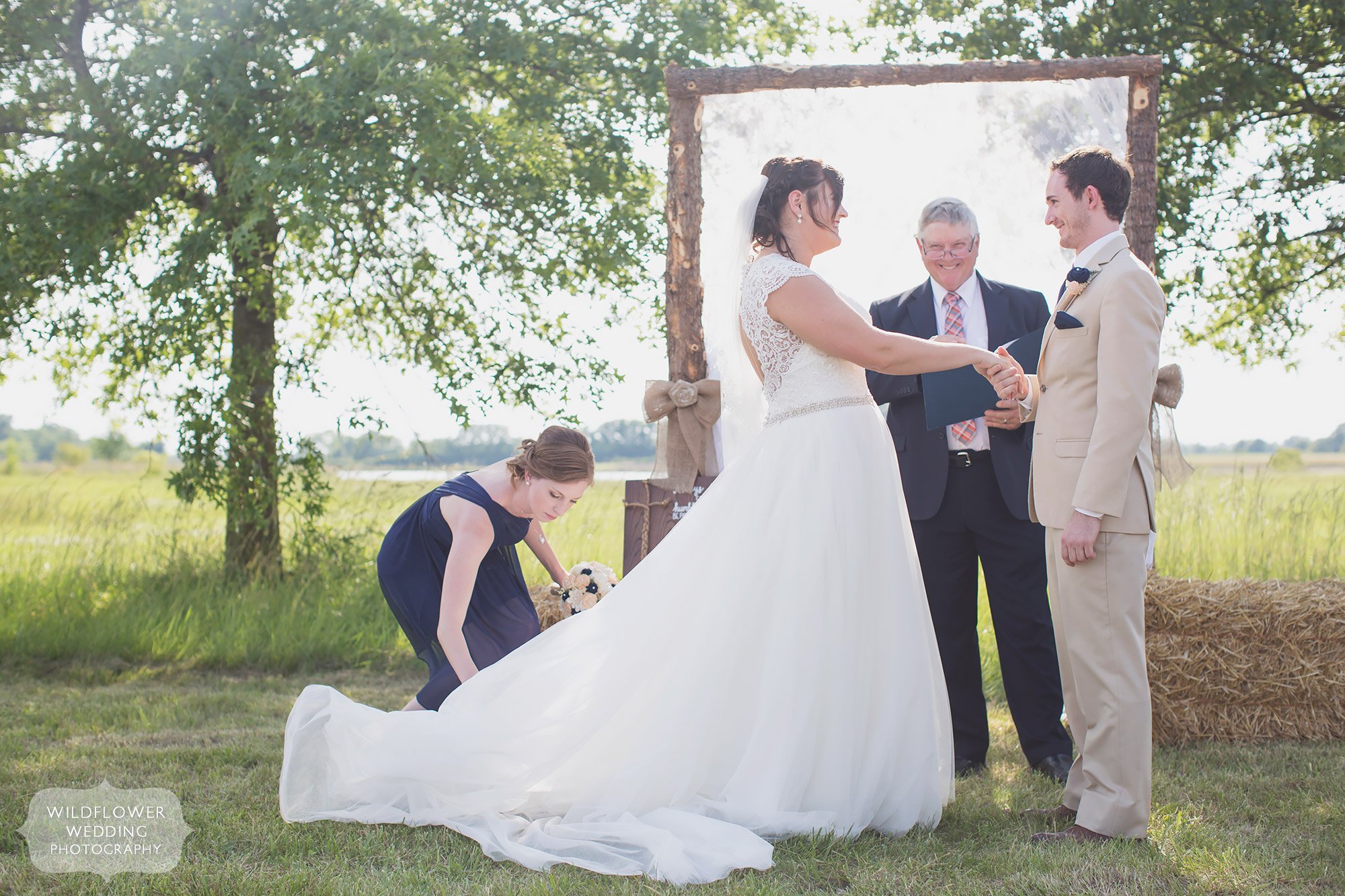 Natural country wedding ceremony in a field with a rustic wood arbor and lace in Columbia, MO.