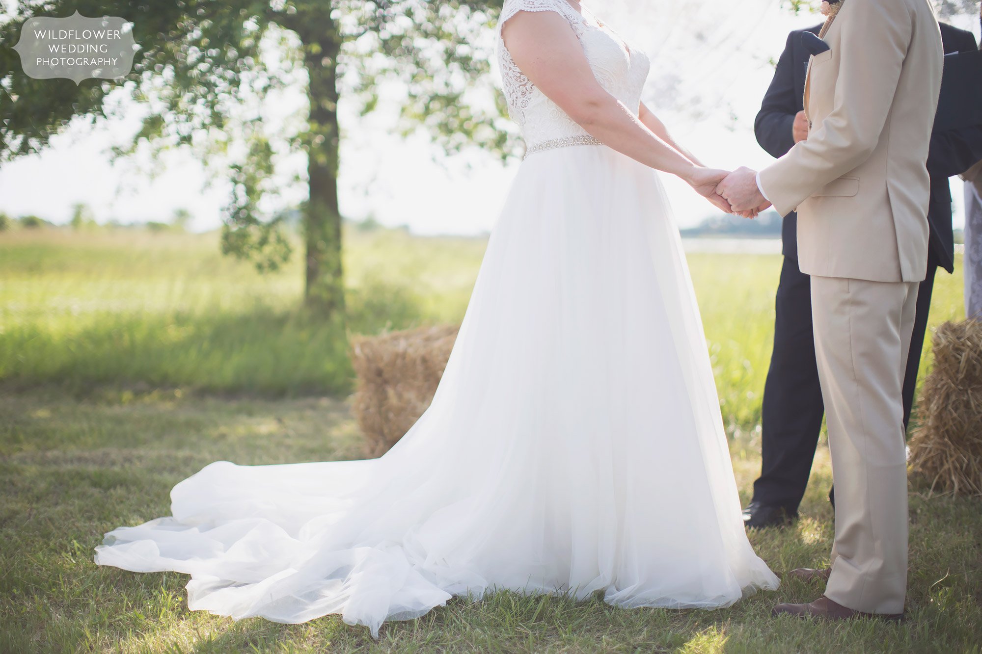 Ethereal wedding photography of the bride and groom holding hands with blurry background during outdoor ceremony at Bradford Farm.