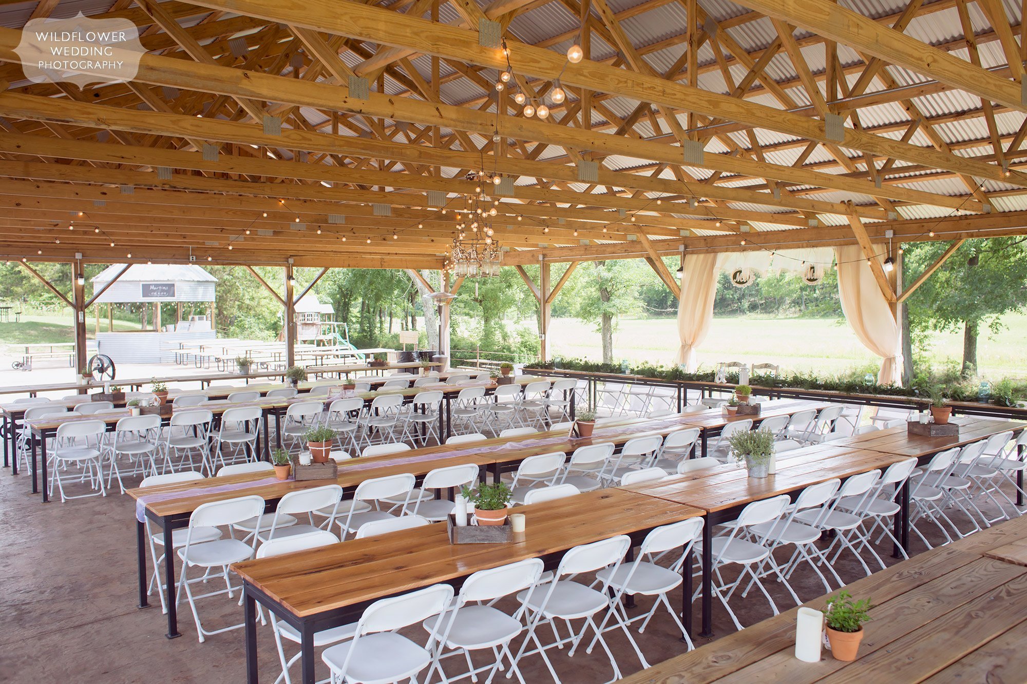 View of the dinner tables set up in the covered pavilion at this barn wedding venue at Kempker's Back 40 in southern MO.
