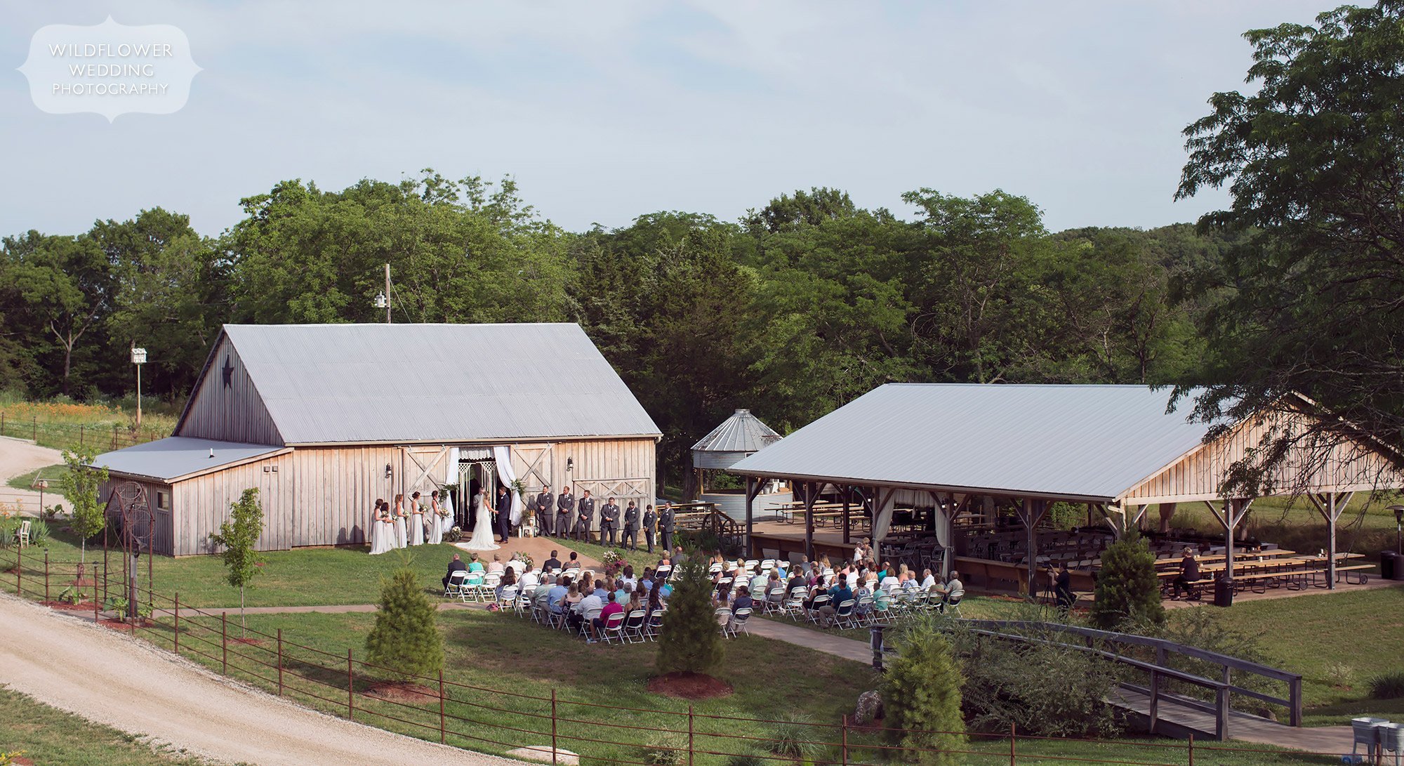 View of the outdoor ceremony in front of the reception barn at Kempker's Back 40, a rustic wedding venue in Westphalia.