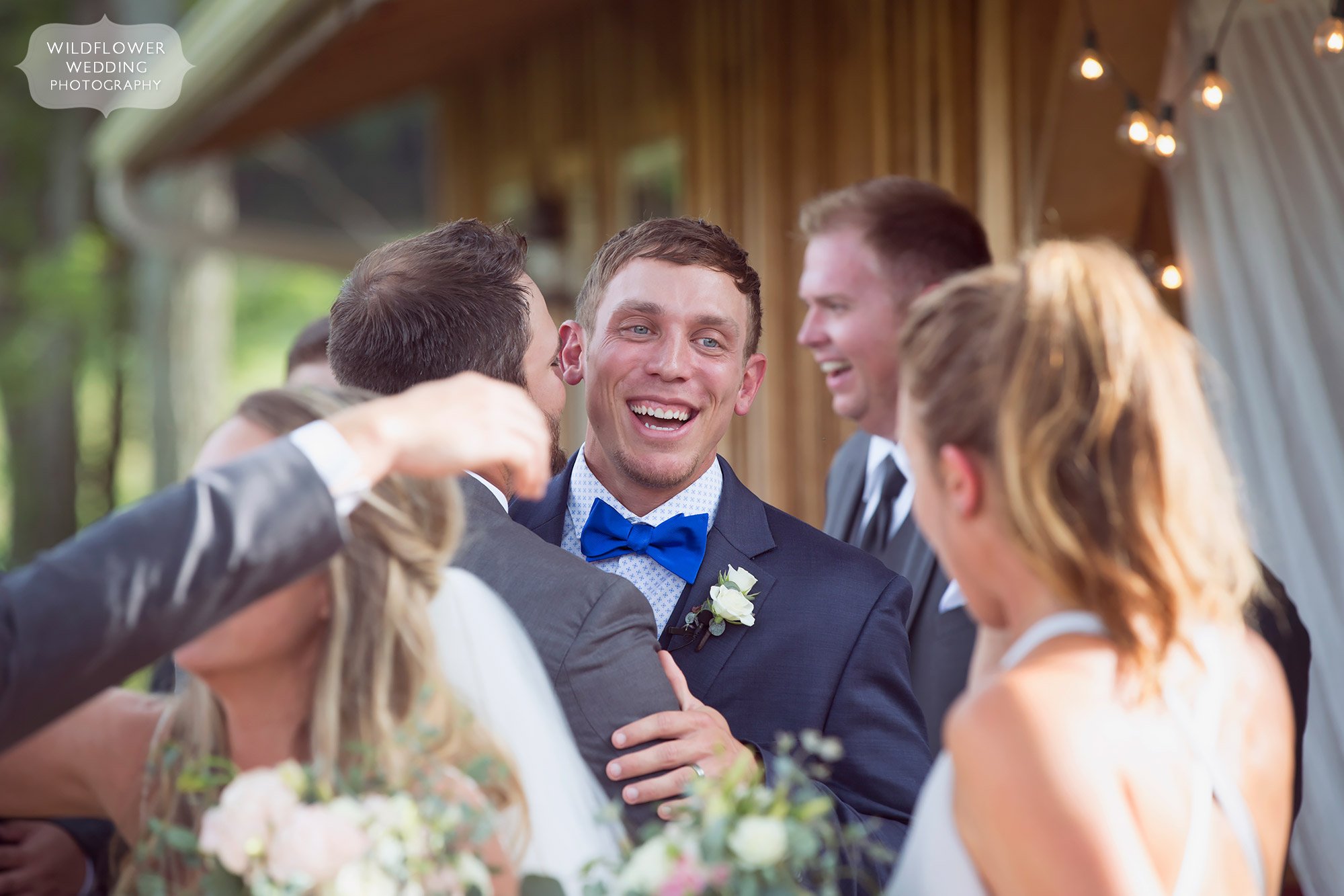 Love this bright and colorful photo of the groom smiling as friends hug him after the barn ceremony in southern MO.