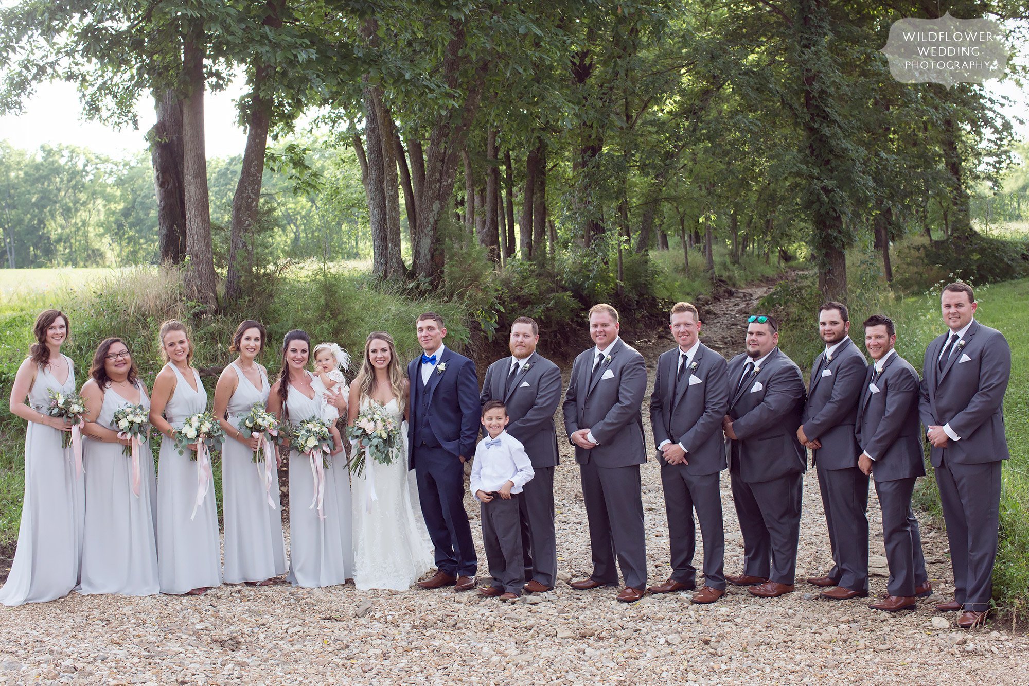 Wedding party poses in the rocky creekbed at this rustic barn wedding venue in Westphalia.