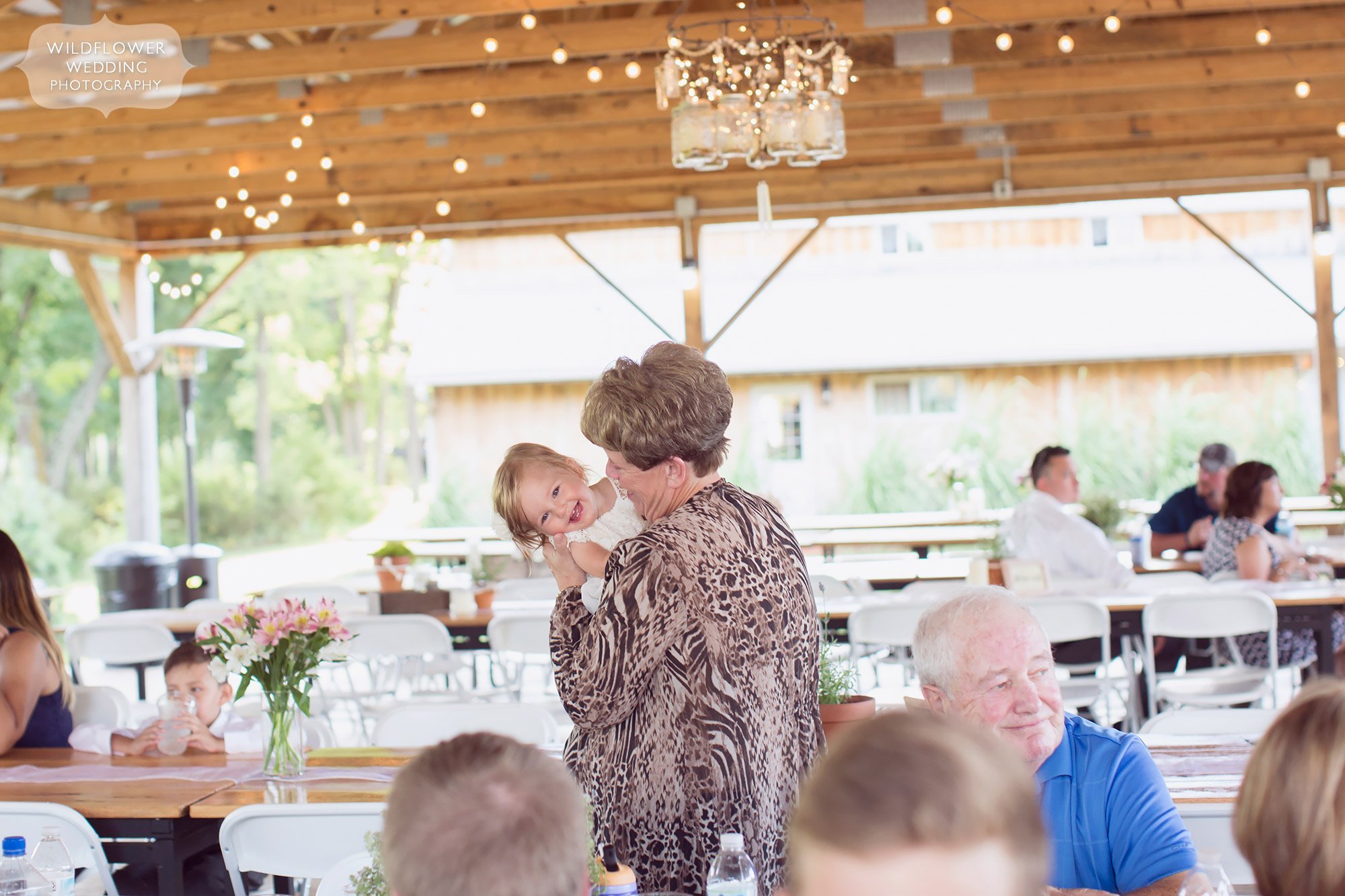 Great documentary wedding photo of the grandmother smiling with her granddaughter after dinner in the covered pavilion at this country wedding venue.