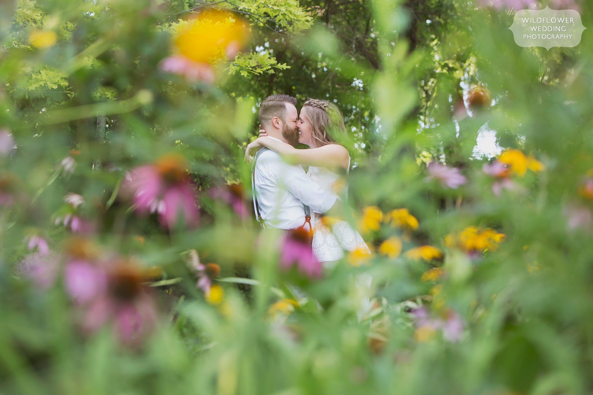 Creative wedding portrait of the bride and groom surrounded by wildflowers for their summer wedding at the Les Bourgeois Winery in Rocheport, MO.