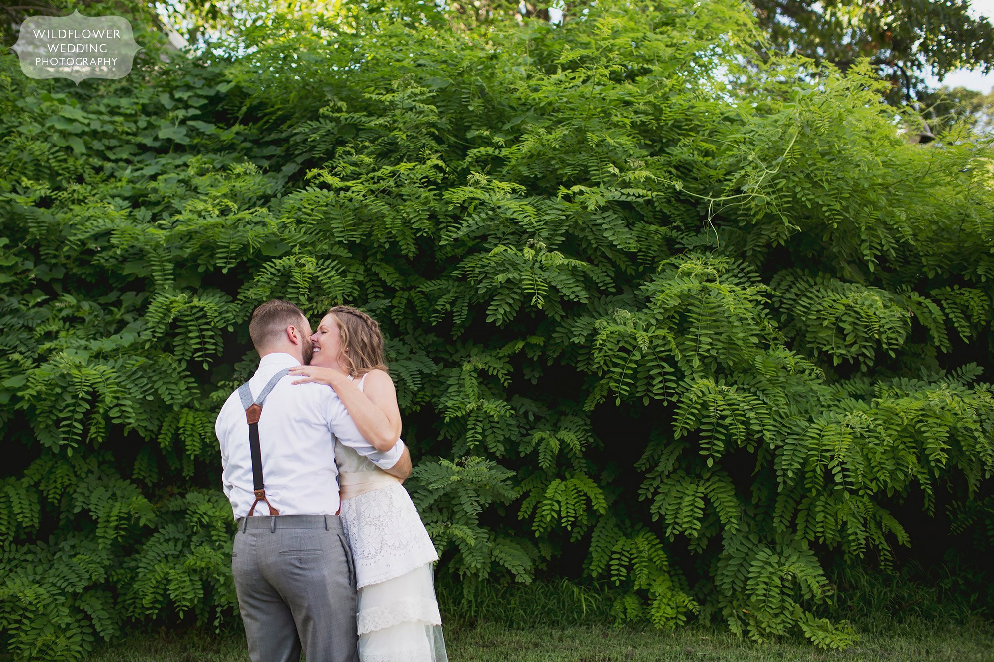 Outdoor wedding photography portrait of the bride and groom dancing in front of a wall of greenery along the Katy Trail in Rocheport, MO.