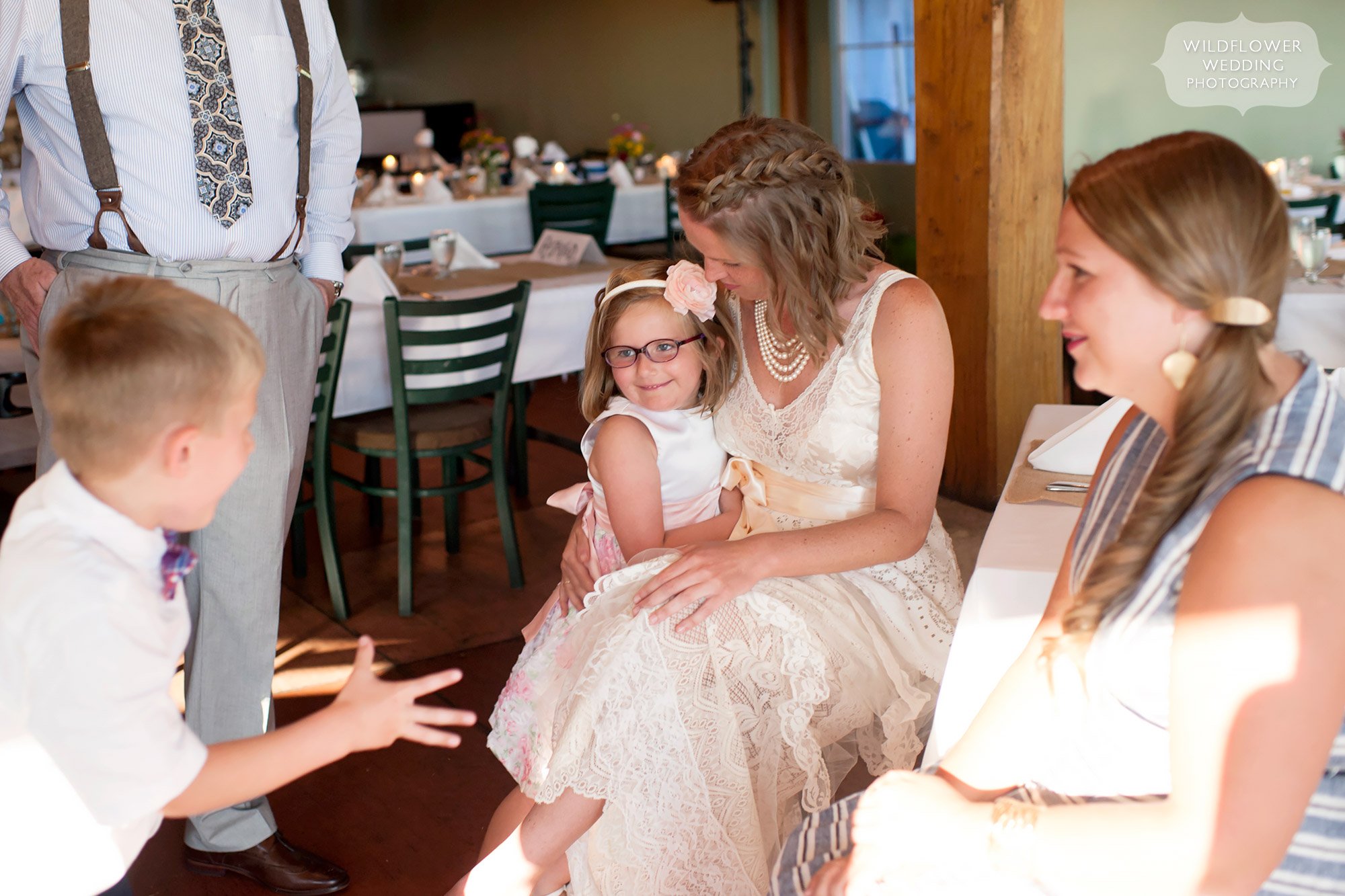 flower girl on bride's lap at summer winery wedding in mo