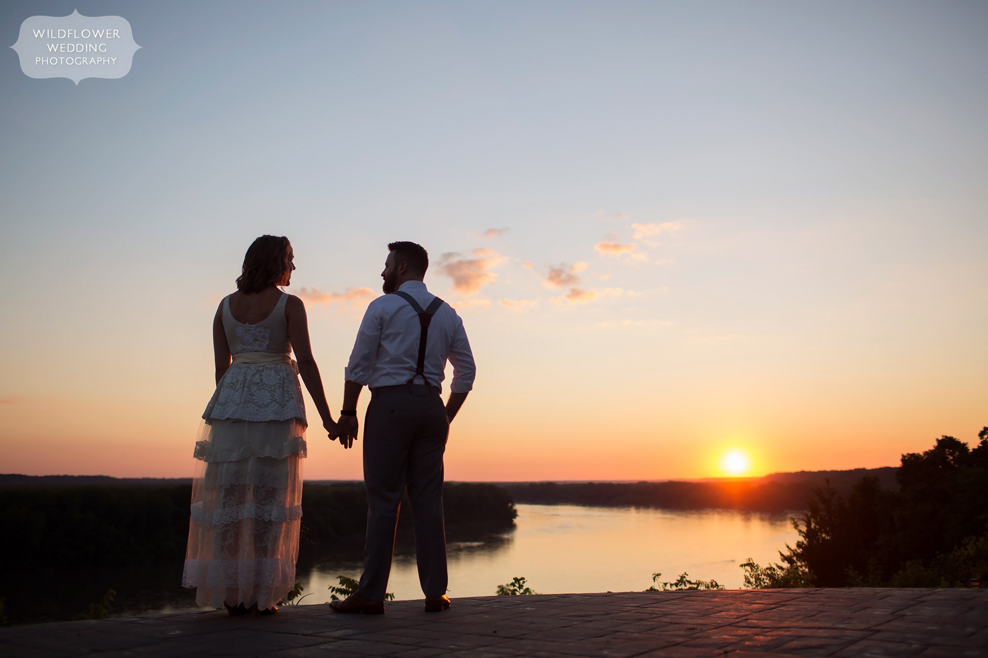 bride and groom silhouette on blufftop at les bourgeois at sunset over missouri river
