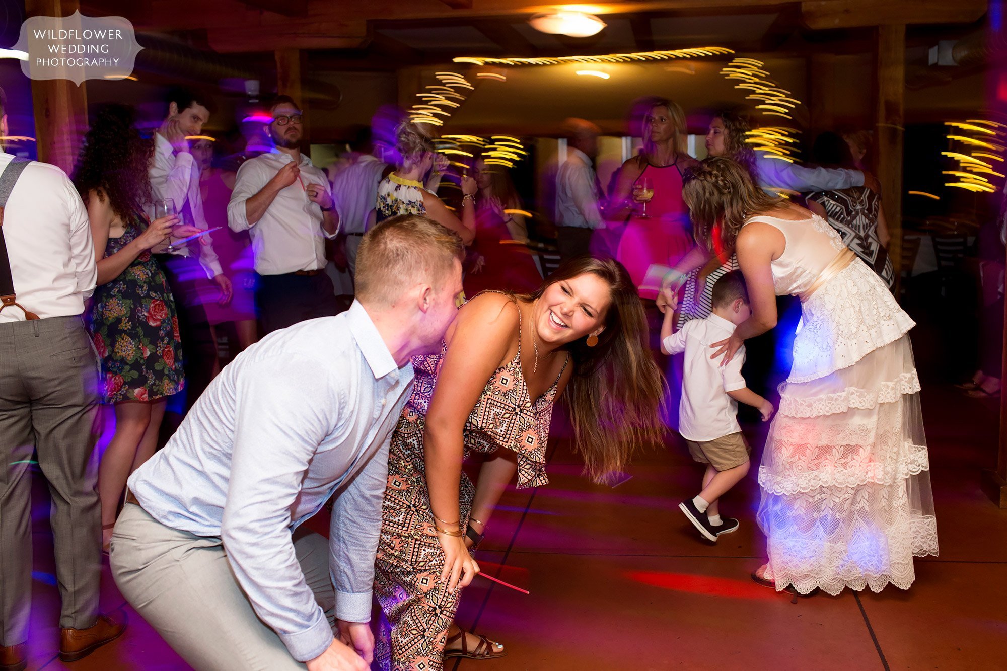 guests dance in the middle of a dance floor with uplighting at les bourgeois