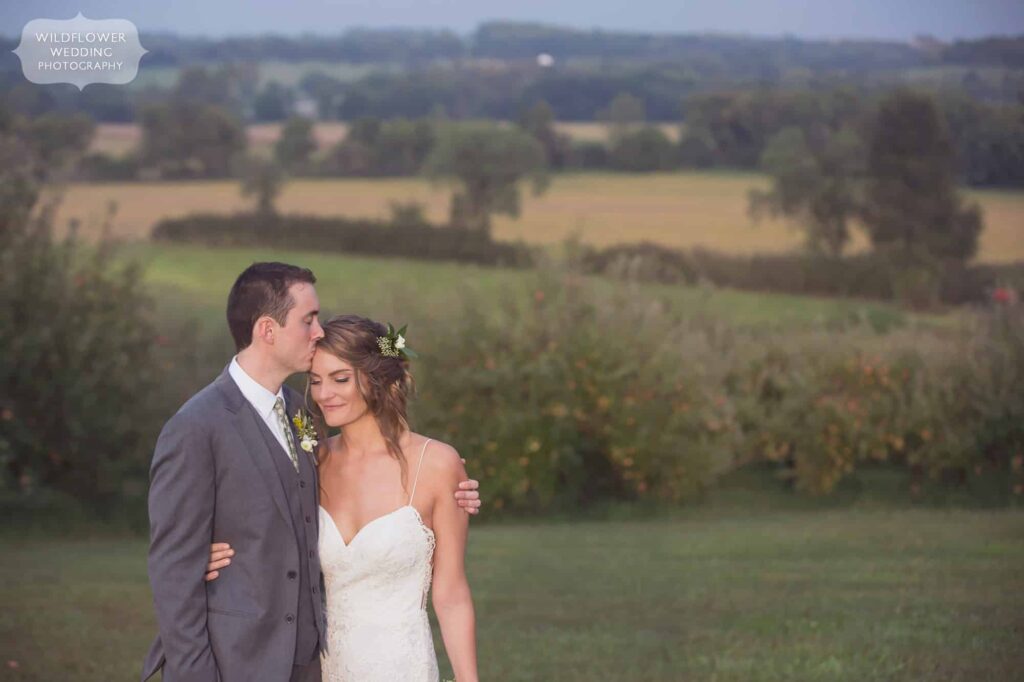 The groom kisses the bride's forehead during a romantic Missouri barn wedding at the Weston Red Barn Farm.