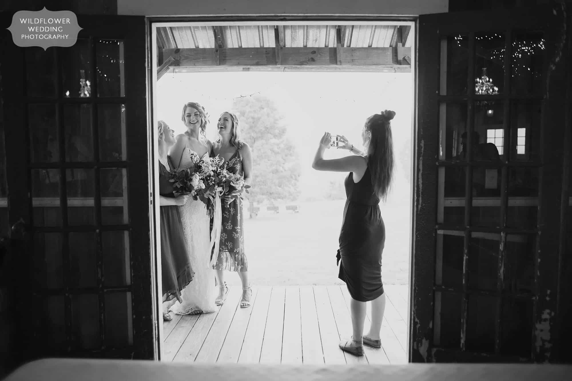 The bride laughs with friends on the porch during a rainy wedding at the Weston Red Barn Farm.