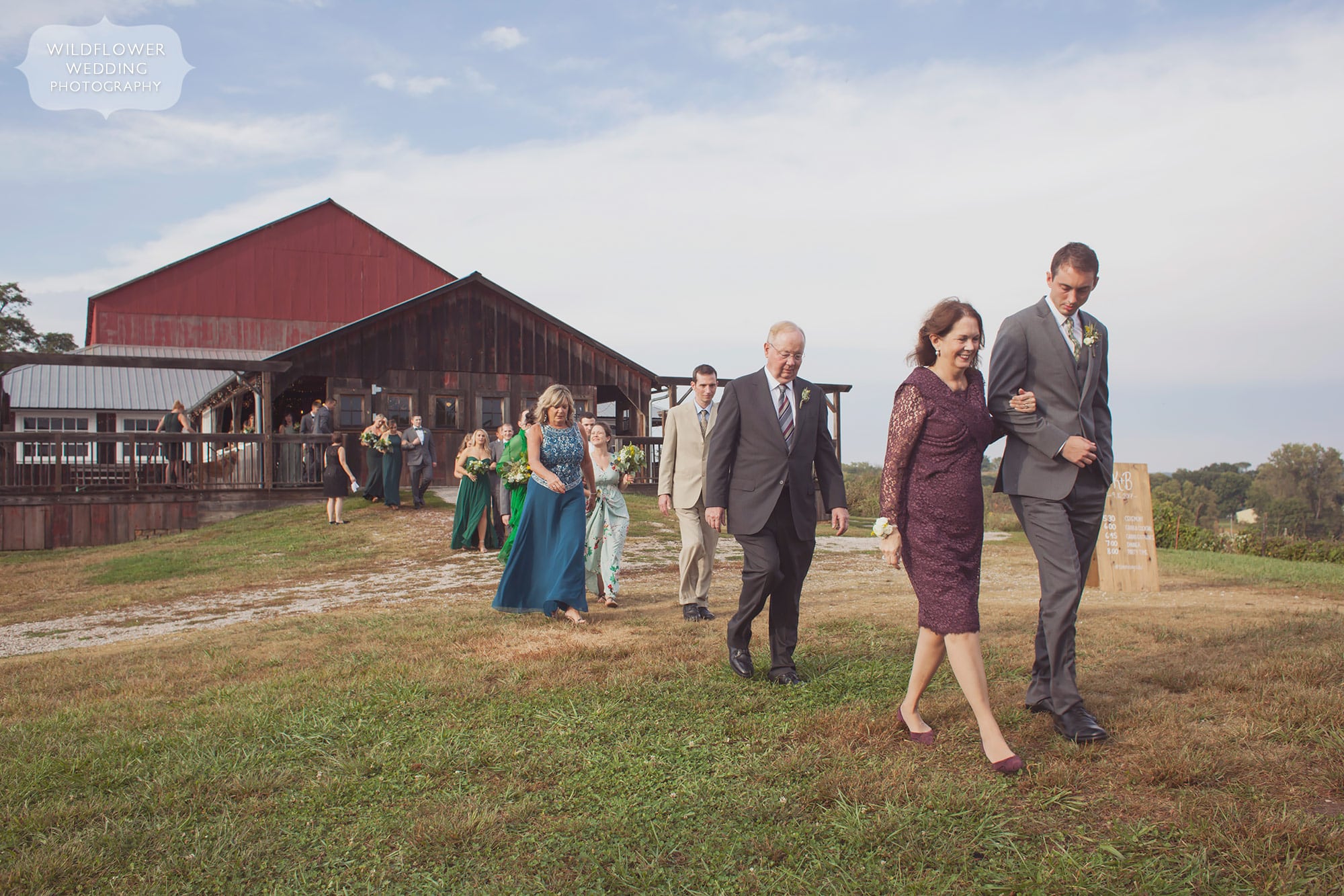 Wedding guests walk toward the orchard for an outdoor ceremony at Weston Red Barn Farm.