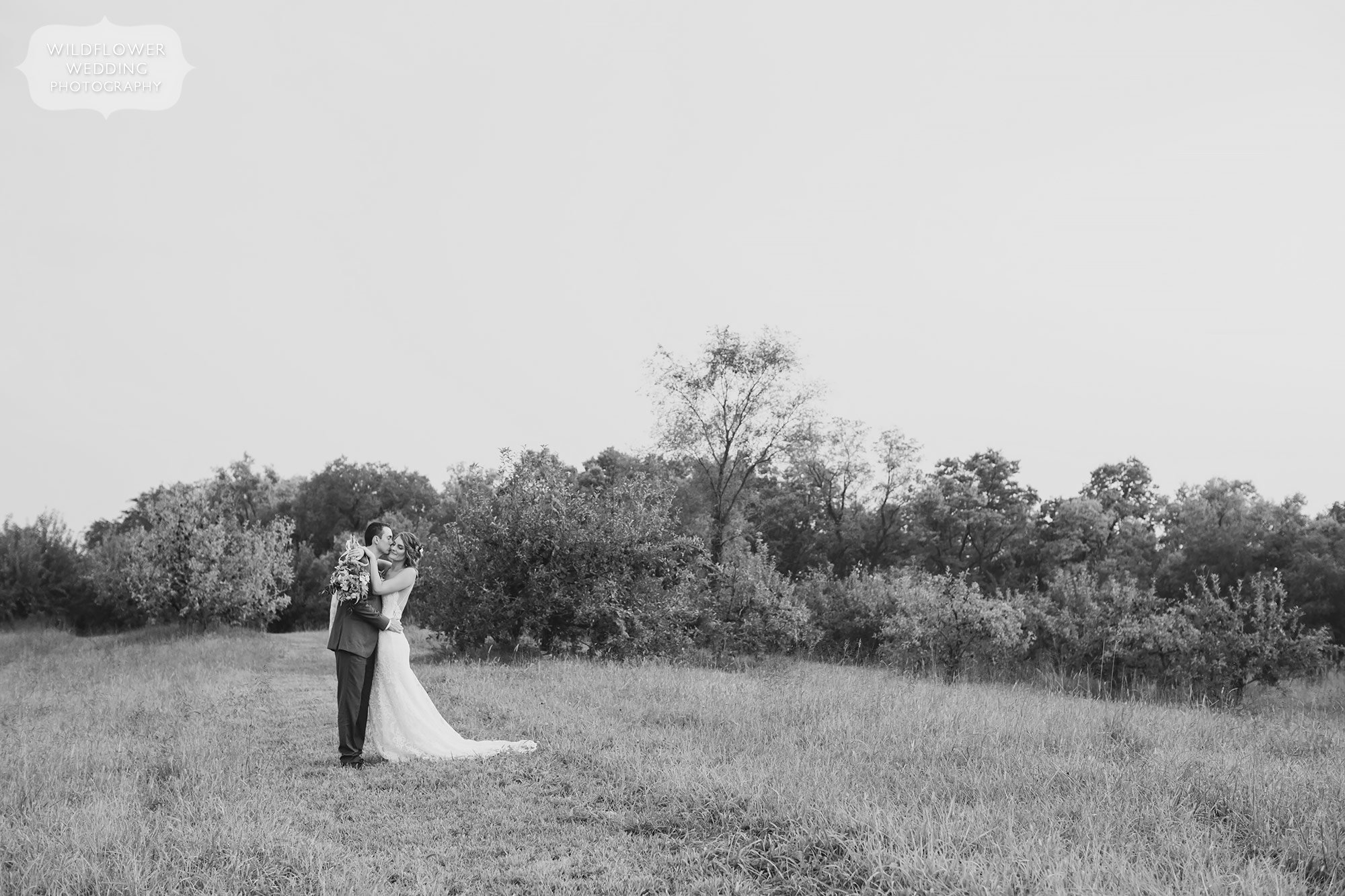 Artistic wedding photography in black and white of the bride and groom hugging in a field at the Weston Red Barn Farm.