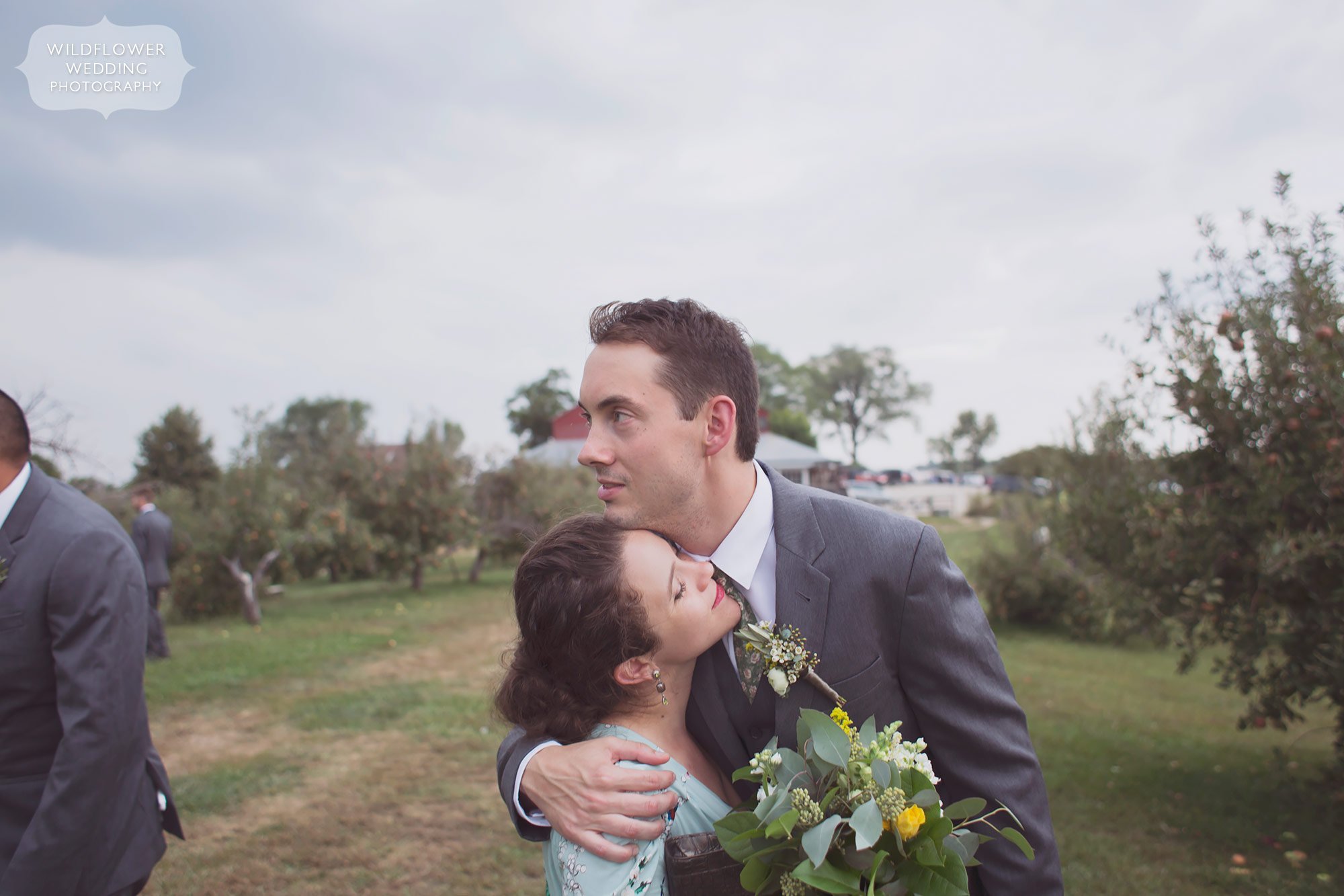 Documentary wedding photography of the groom hugging his best friend at the Weston Red Barn Farm.