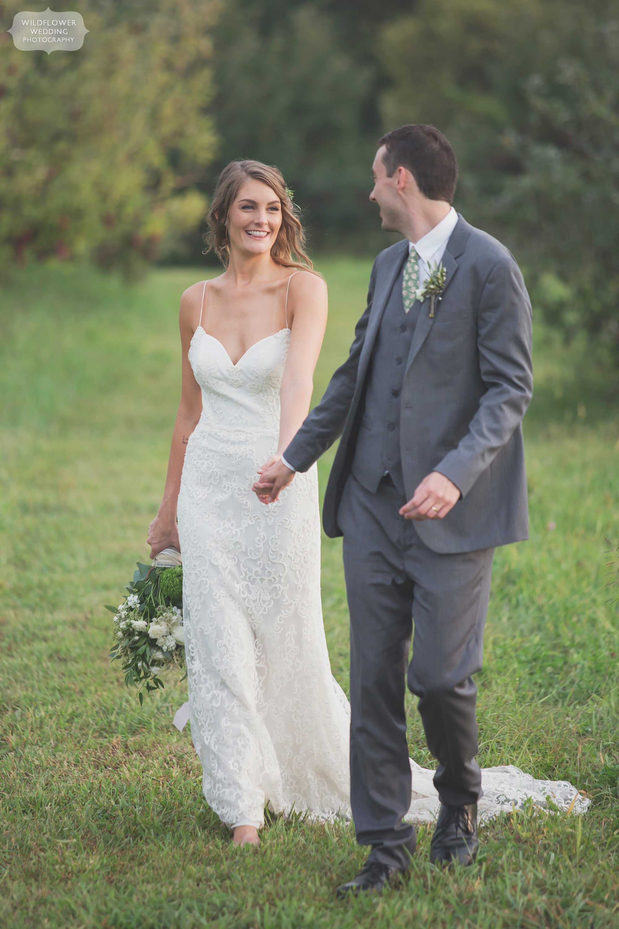 The groom leading the bride through a tall grass field at this barn wedding in Weston.