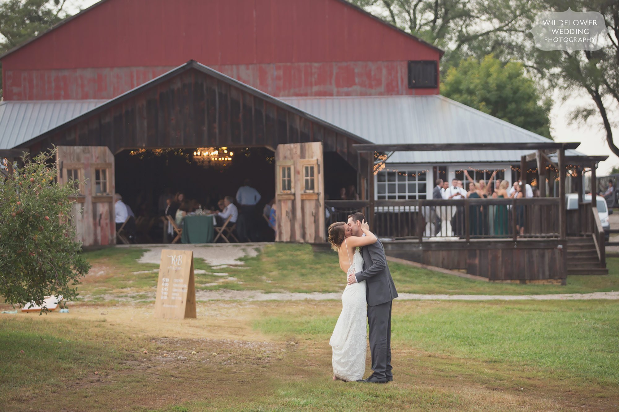 The bride and groom kiss in front of the old barn at the Weston Red Barn Farm in MO.