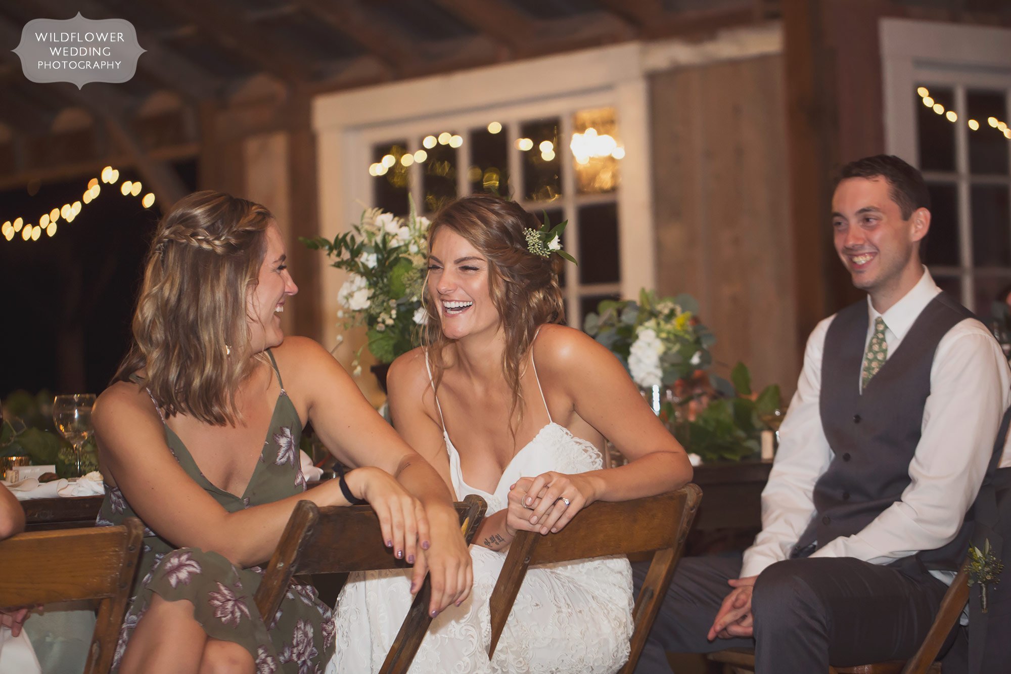 Bride laughing at toasts inside of the cozy barn wedding venue in Weston, MO.