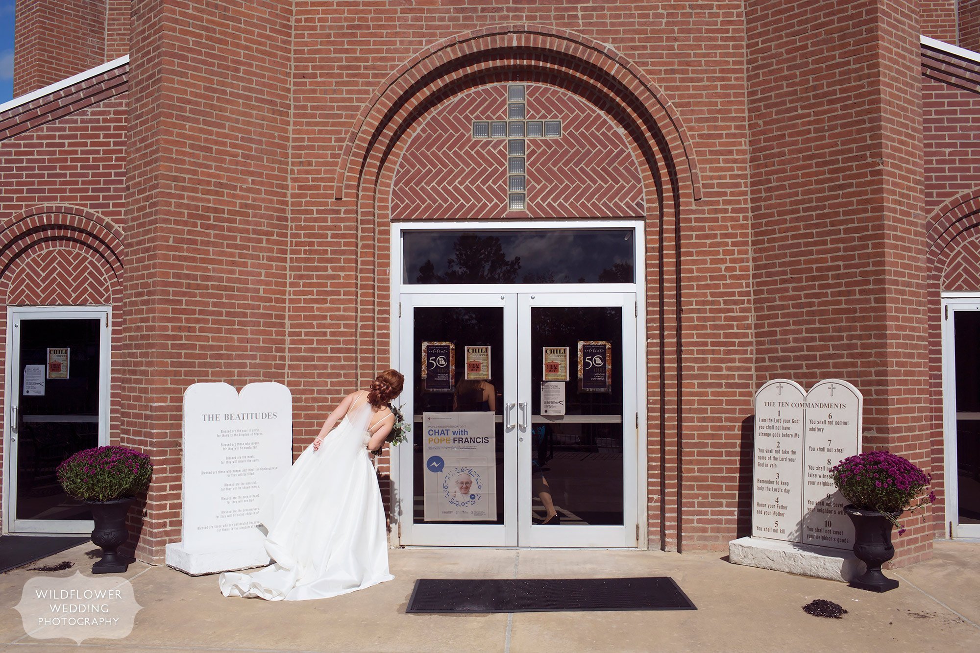 Great documentary wedding photo of the bride looking in the windows of the church before her Jeff City, MO wedding.