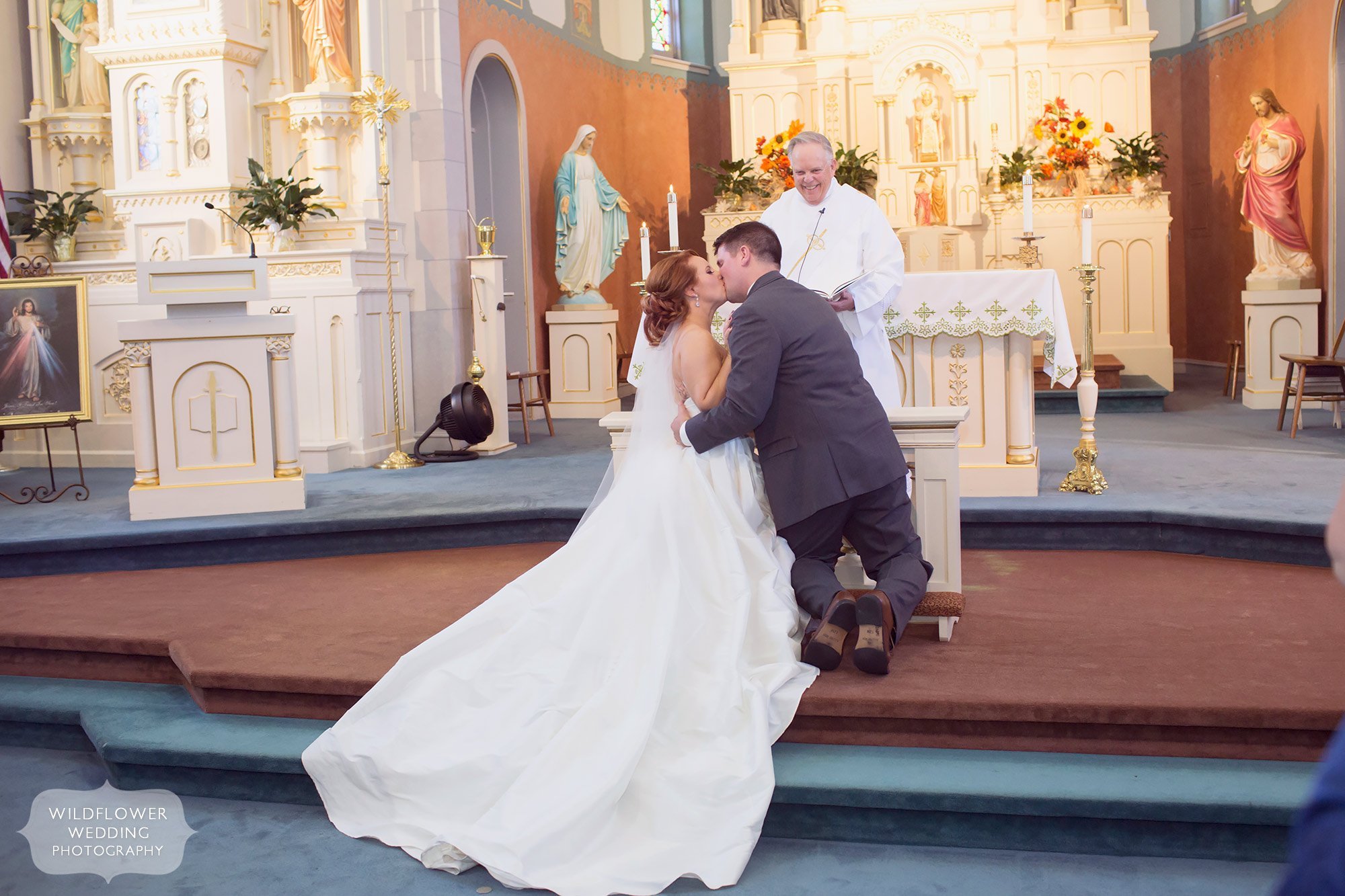 Bride and groom have a kneeling kiss at their church wedding in Jeff City.