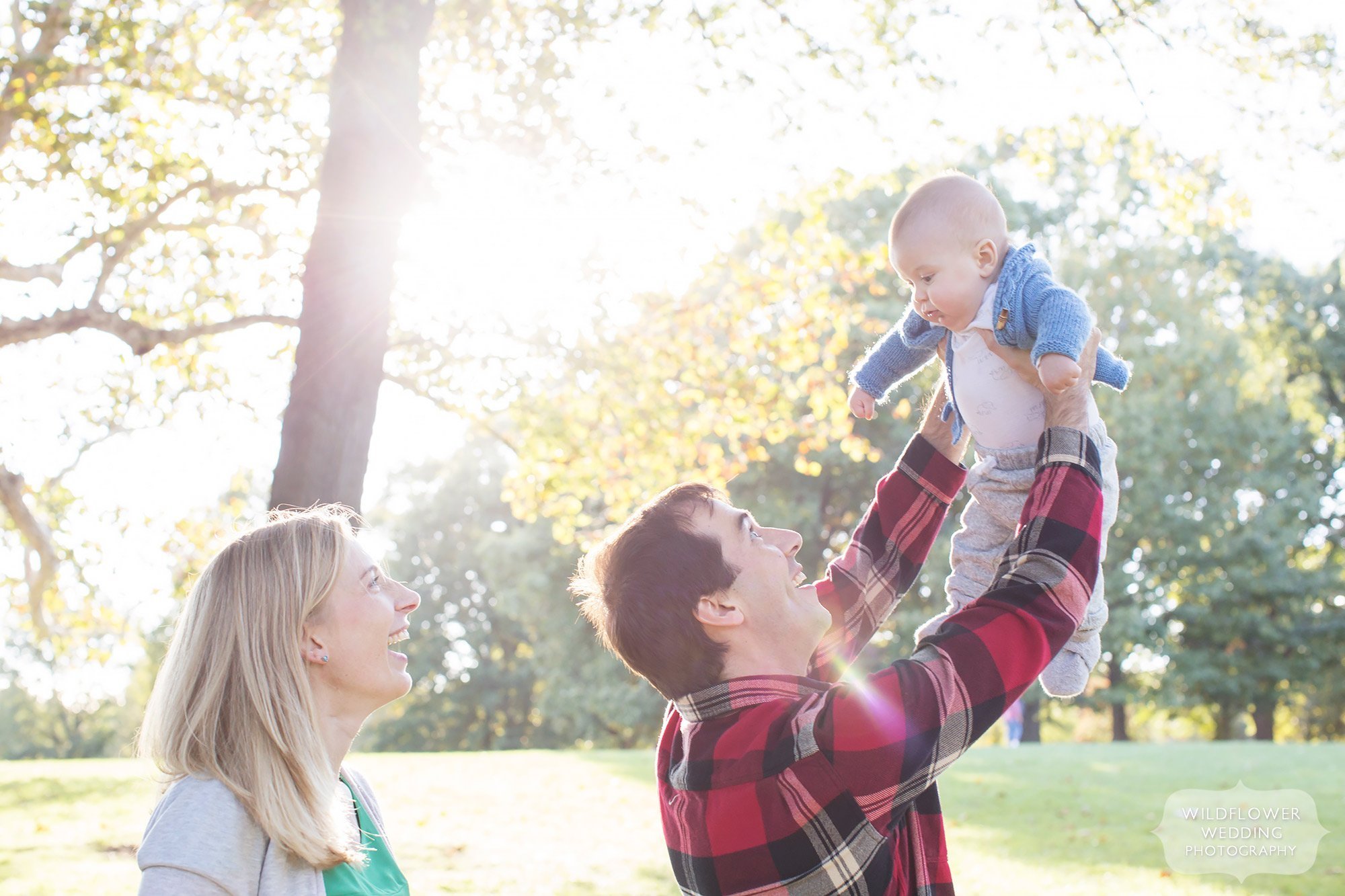 The dad lifts up his baby in the air during this family portrait shoot in KC.